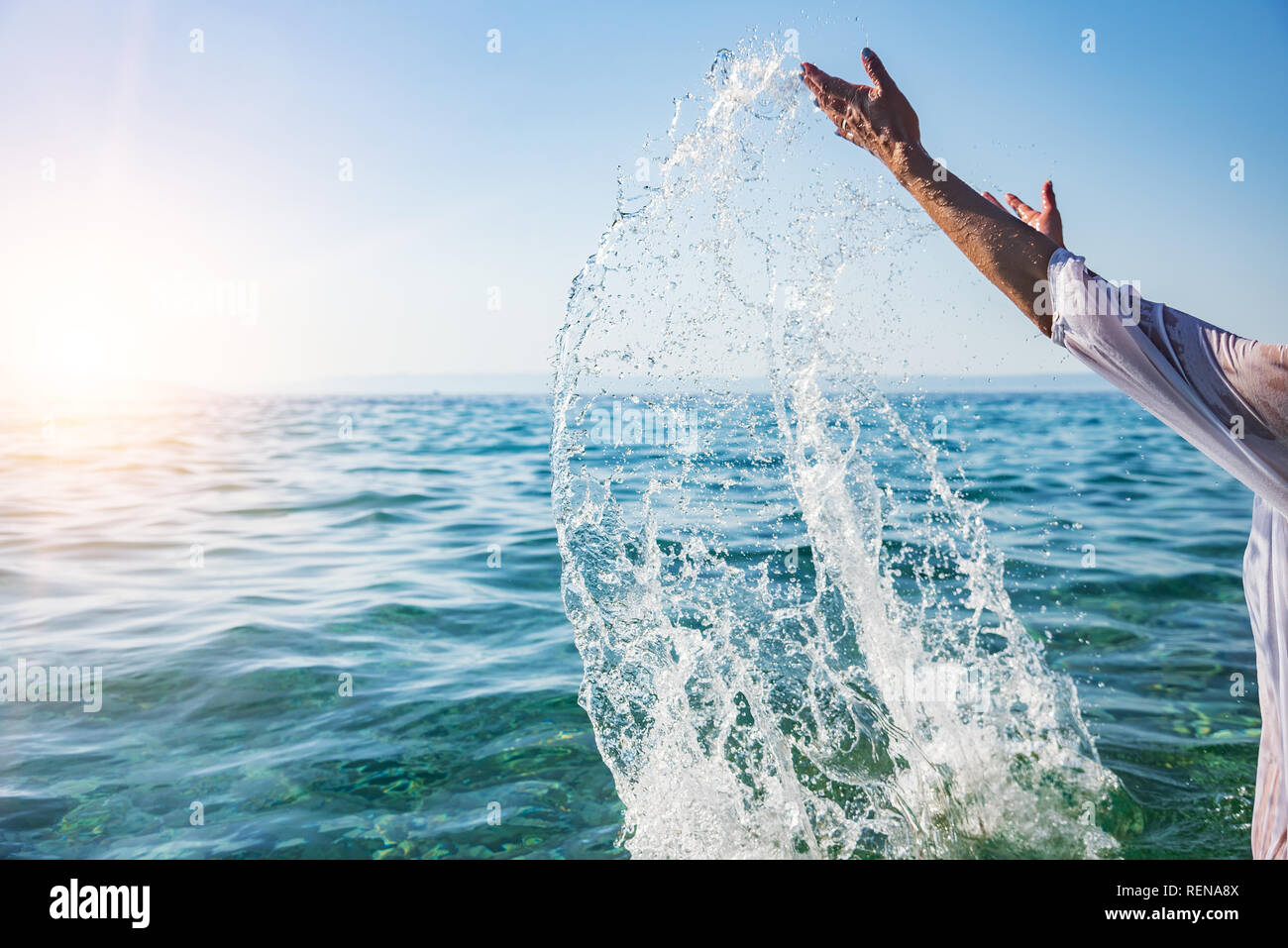 Donna mani gli spruzzi di acqua di mare. Vacanze al concetto di resort. Foto Stock