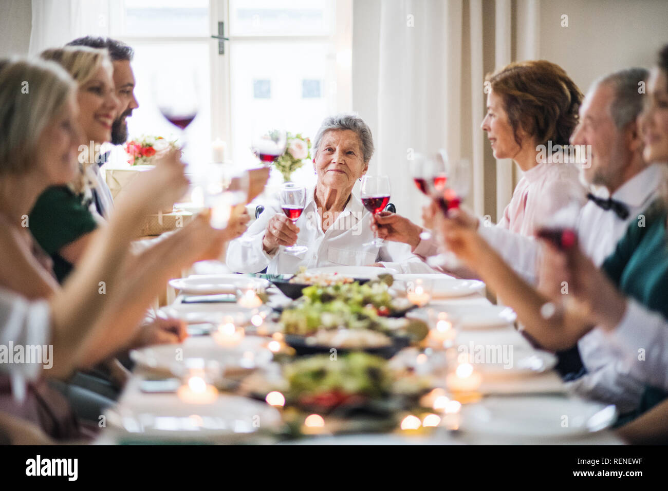 Una grande famiglia seduti a un tavolo in una piscina festa di compleanno, bicchieri tintinnanti. Foto Stock