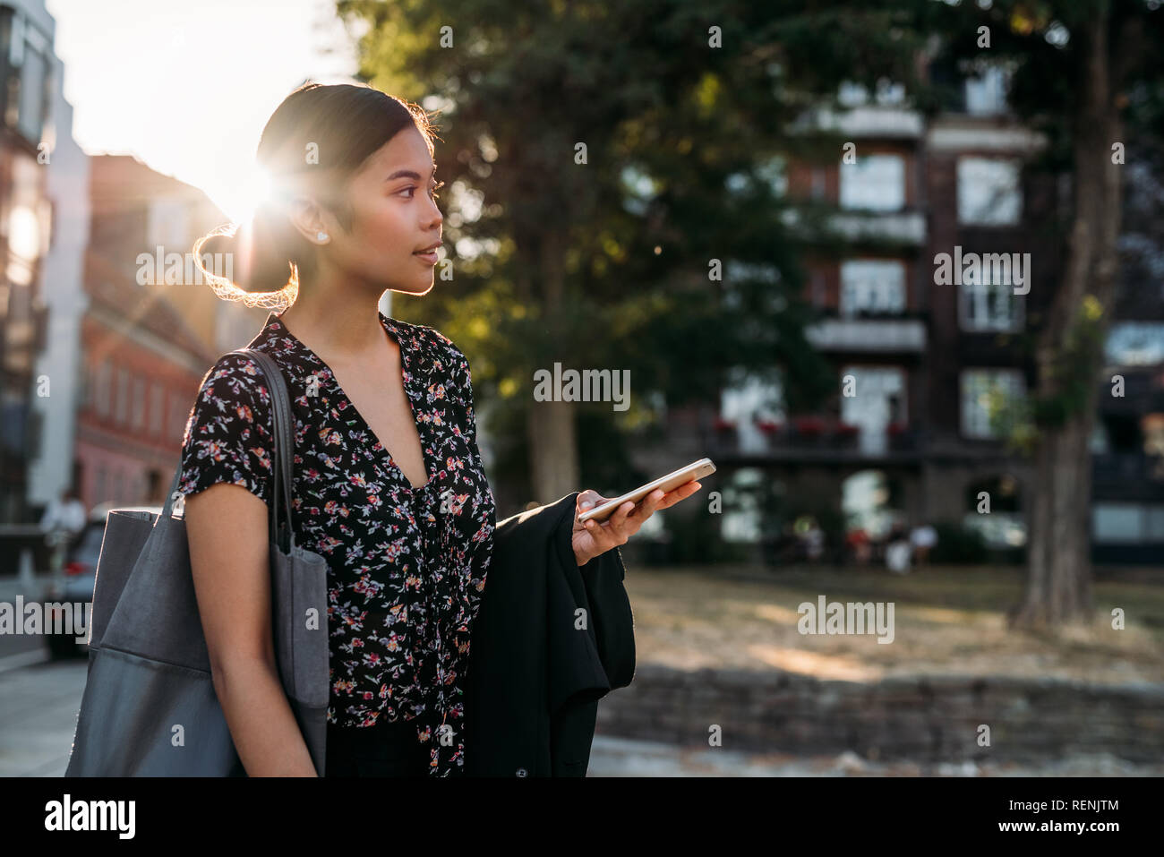 Giovane imprenditrice asiatici in piedi fuori dopo il lavoro utilizzando il suo telefono cellulare Foto Stock