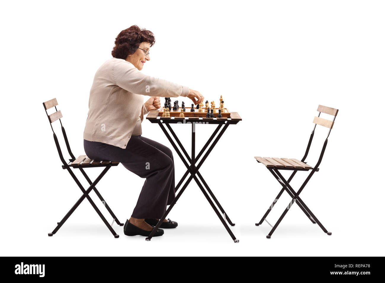 Lunghezza piena ripresa del profilo di una donna senior giocando a scacchi a un tavolo isolato su sfondo bianco Foto Stock