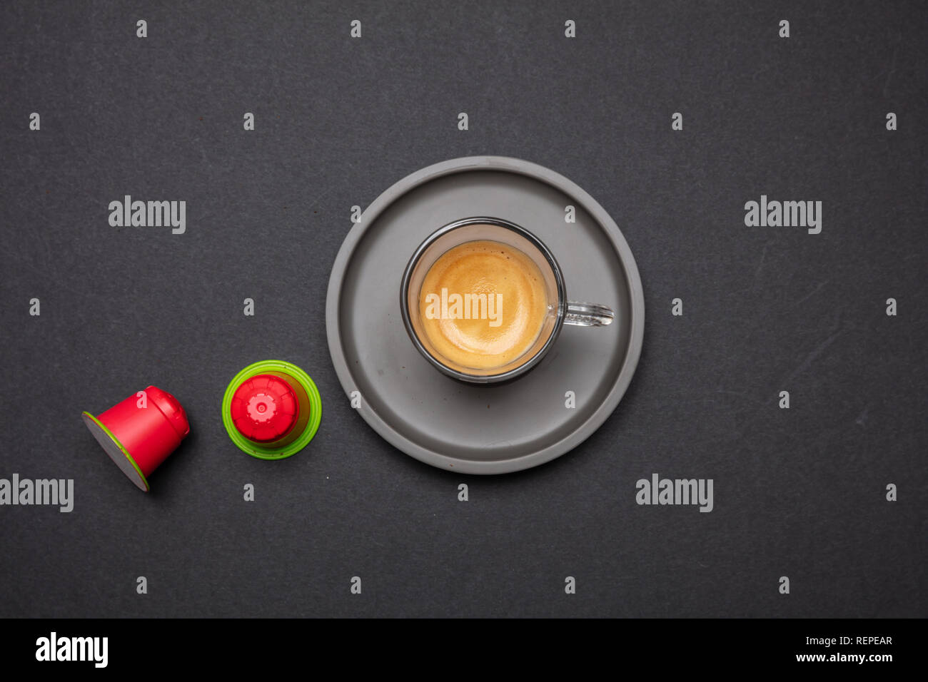 Tazza di caffè e red compostabile capsule e cialde, su nero colore di sfondo, vista dall'alto Foto Stock