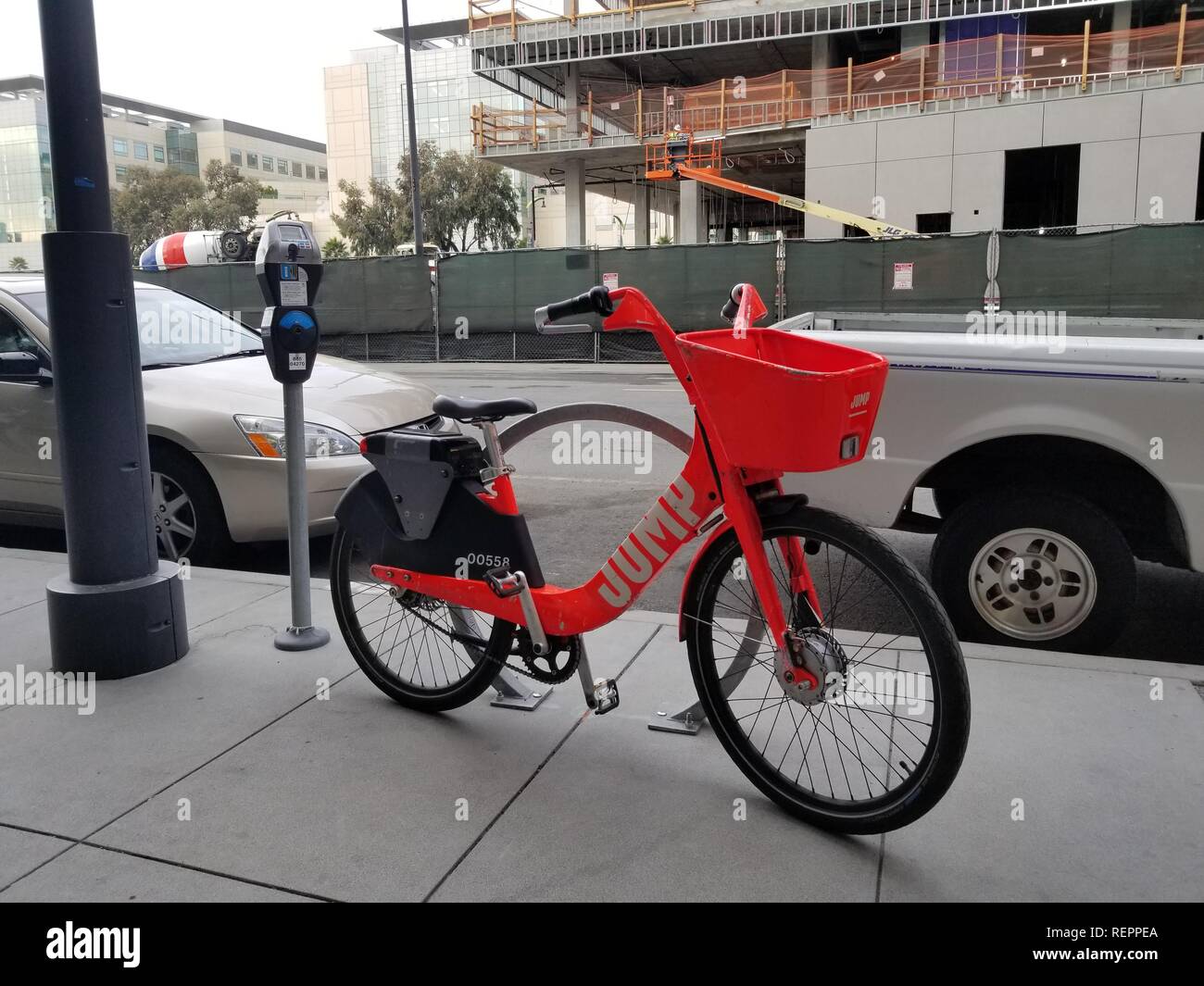 Fotografia di close-up di un arancione di proprietà di bicicletta da corsa-società di condivisione Jump, parcheggiate sul marciapiede accanto a una bicicletta stare sulla Terza Strada, attraversata dalla UCSF Servizi di Medicina del Lavoro, situato nella baia di missione del Distretto di San Francisco, California, 29 ottobre 2018. () Foto Stock
