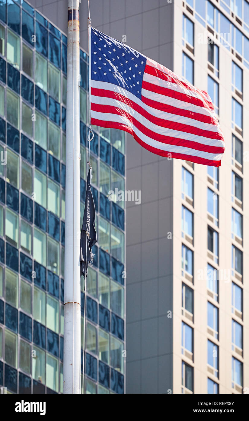 Battenti bandiera americana con edifici moderni in background, il fuoco selettivo, New York, Stati Uniti d'America. Foto Stock