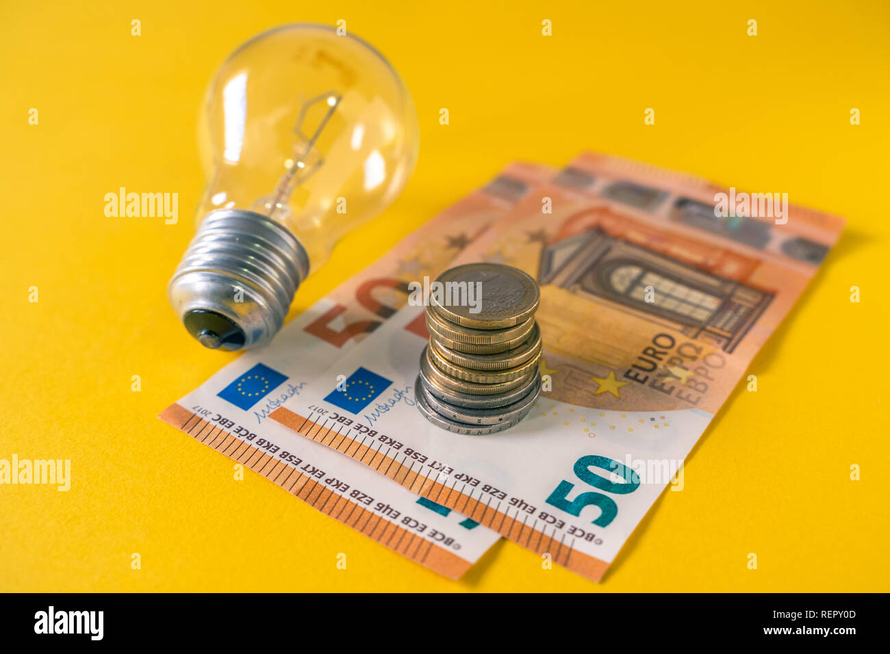La lampadina della spia e unione di banconote e monete in euro. E27. Spiralato filamenti di tungsteno. Foto Stock