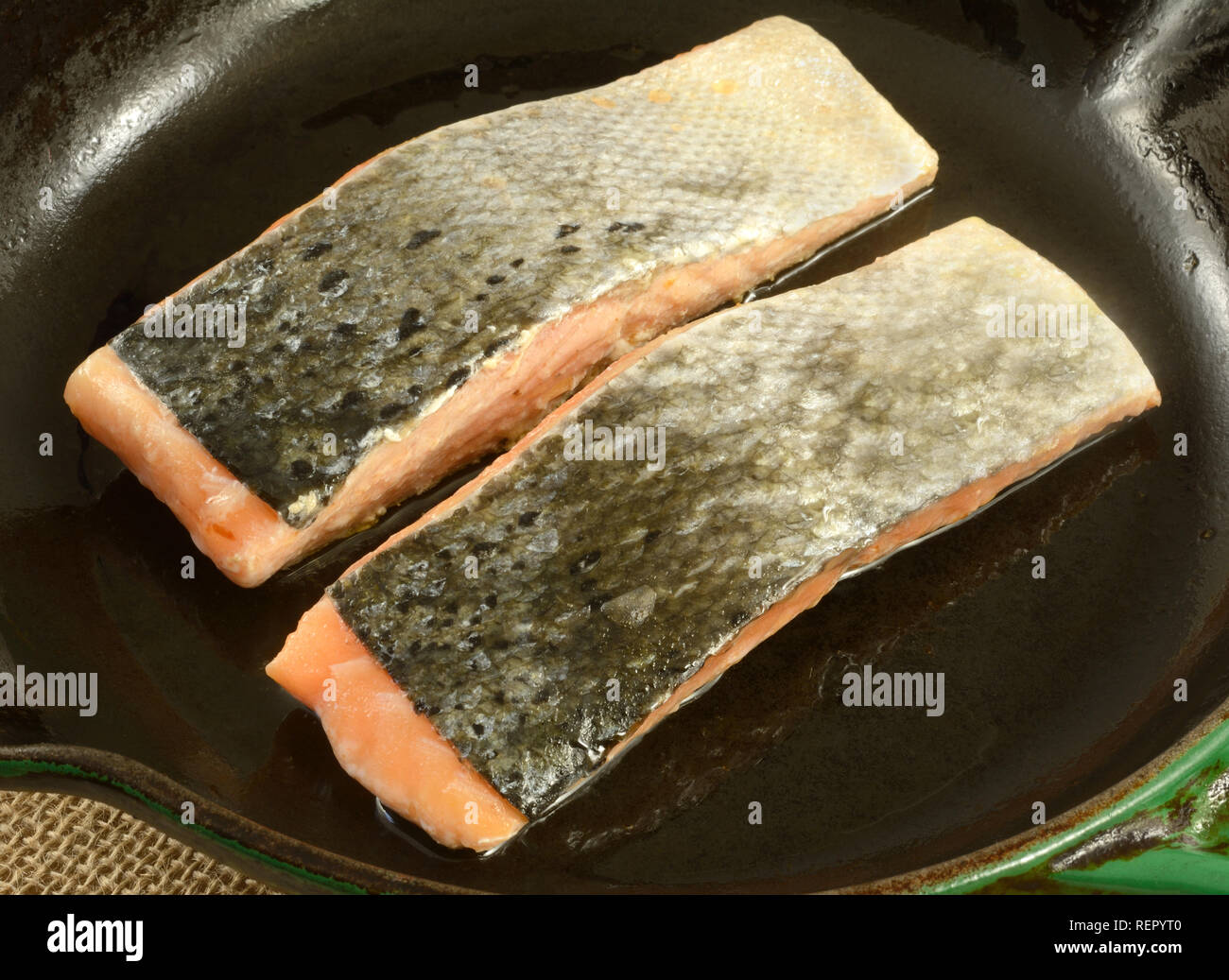In prossimità delle due materie di salmone filetti di pesce lato di pelle fino in ghisa padella rivestita in olio di oliva Foto Stock