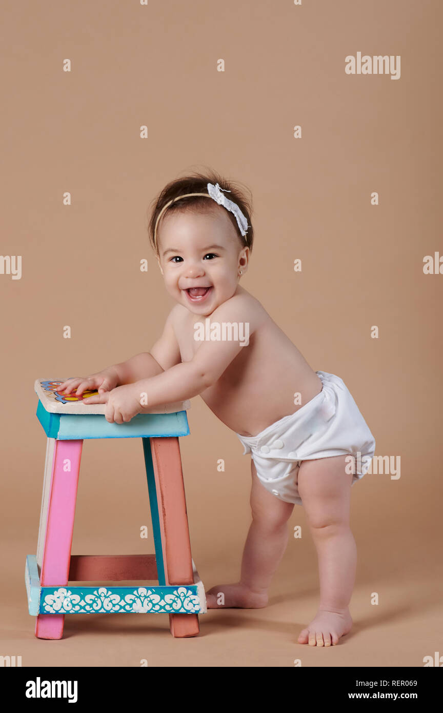 Ampia piuttosto sorridente bambina su marrone di sfondo per studio Foto Stock