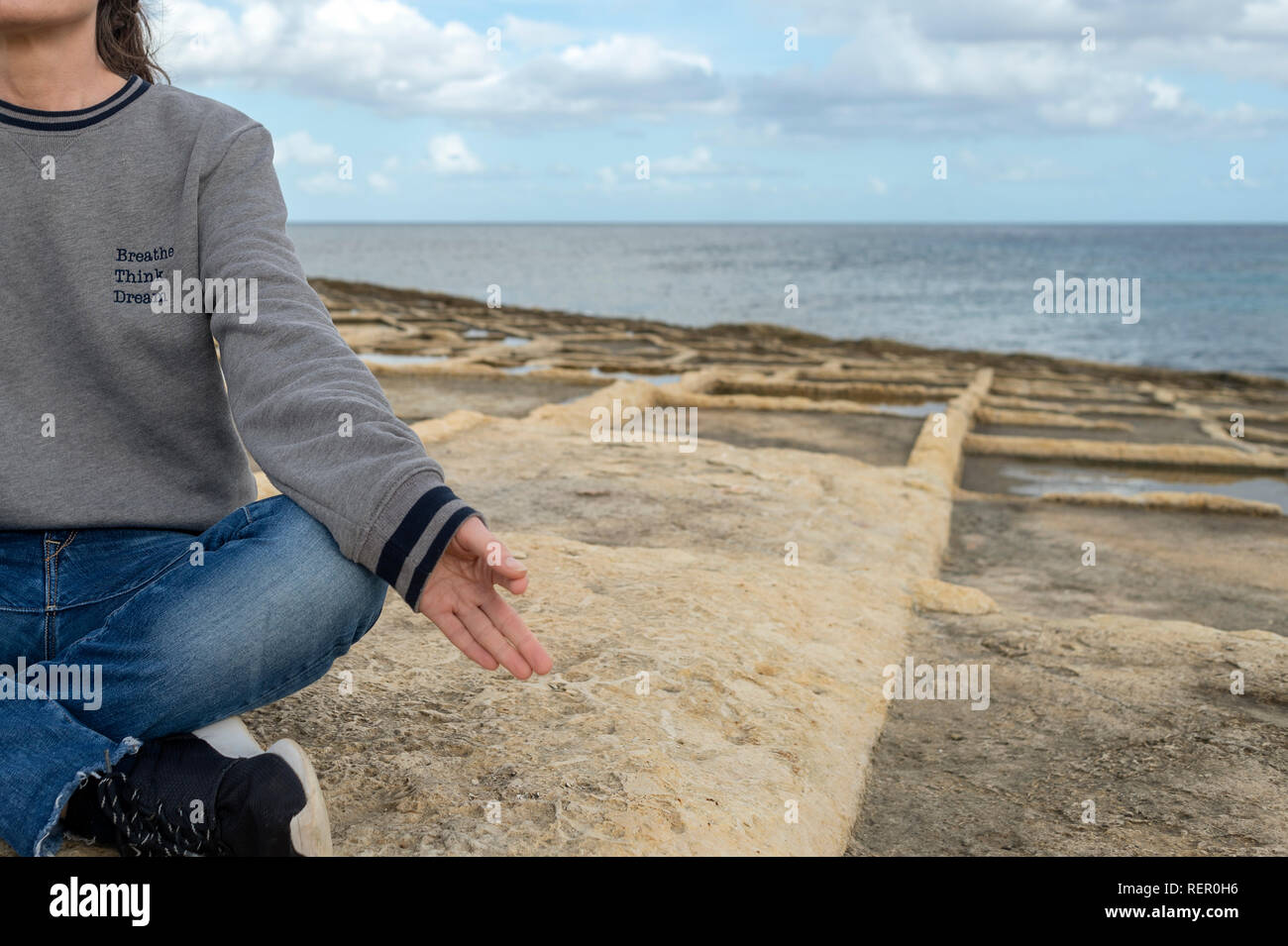 In prossimità di una donna meditando sul mare indossando una felpa con lo slogan "respirare, pensare, sogno" Foto Stock