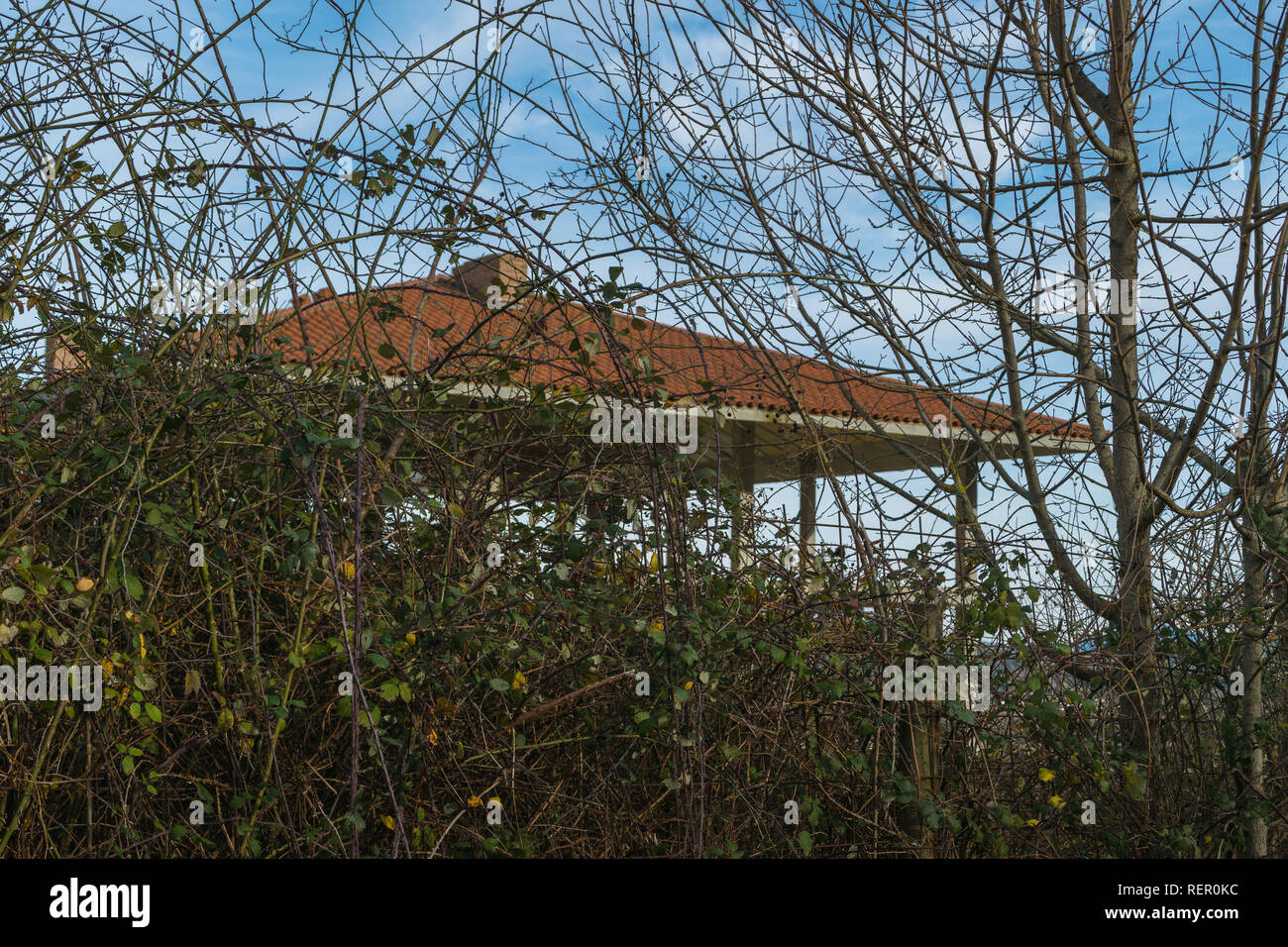 Unbuilt casa in campagna in una giornata di sole con alberi. Una struttura in cemento armato e la copertura del tetto rosso piastrella in campagna Foto Stock