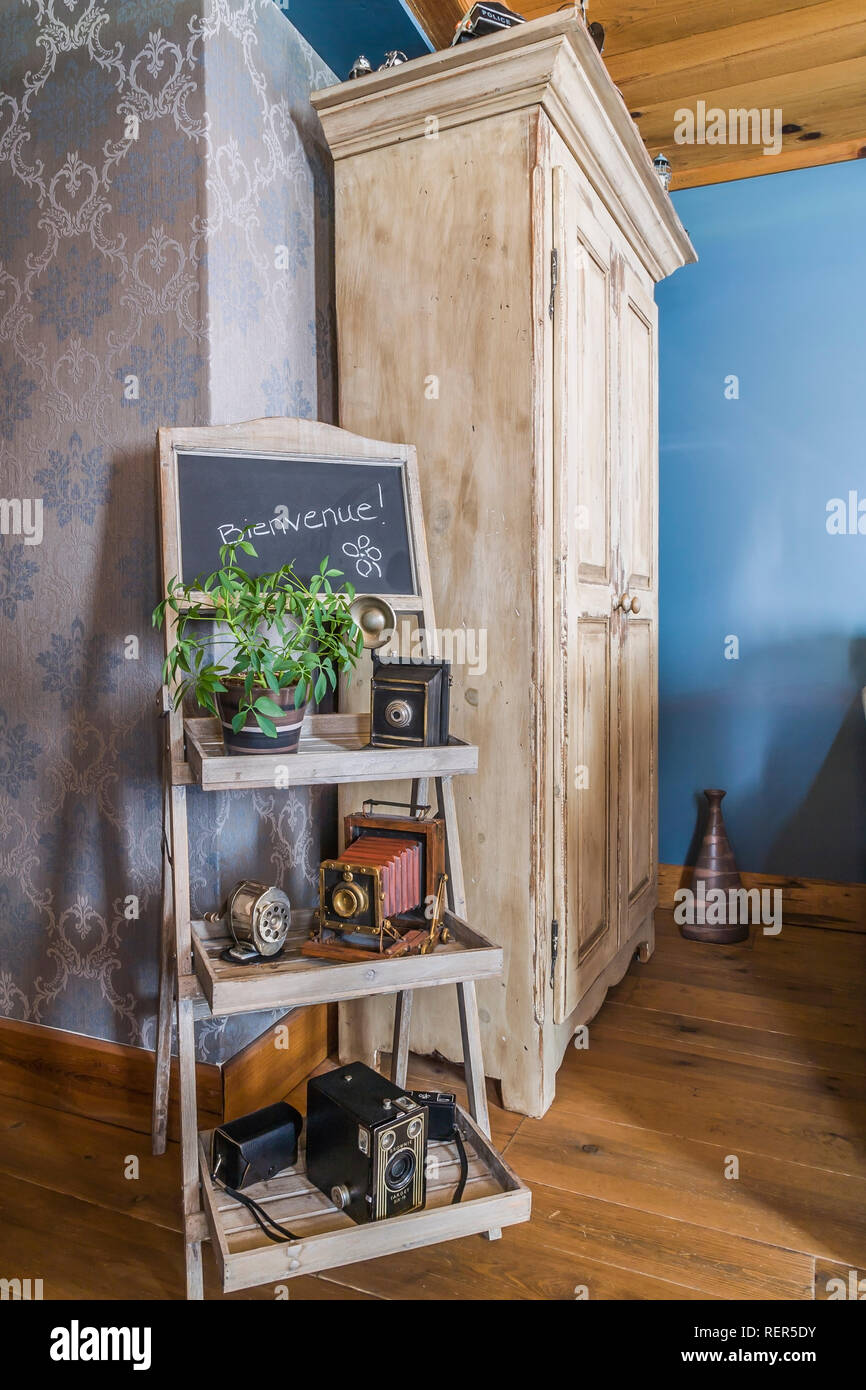 Vecchio vassoio in legno con cavalletto visualizzati antichi telecamere film accanto a tall armadio in legno in soggiorno all'interno di un vecchio 1839 Canadiana cottage in stile home Foto Stock