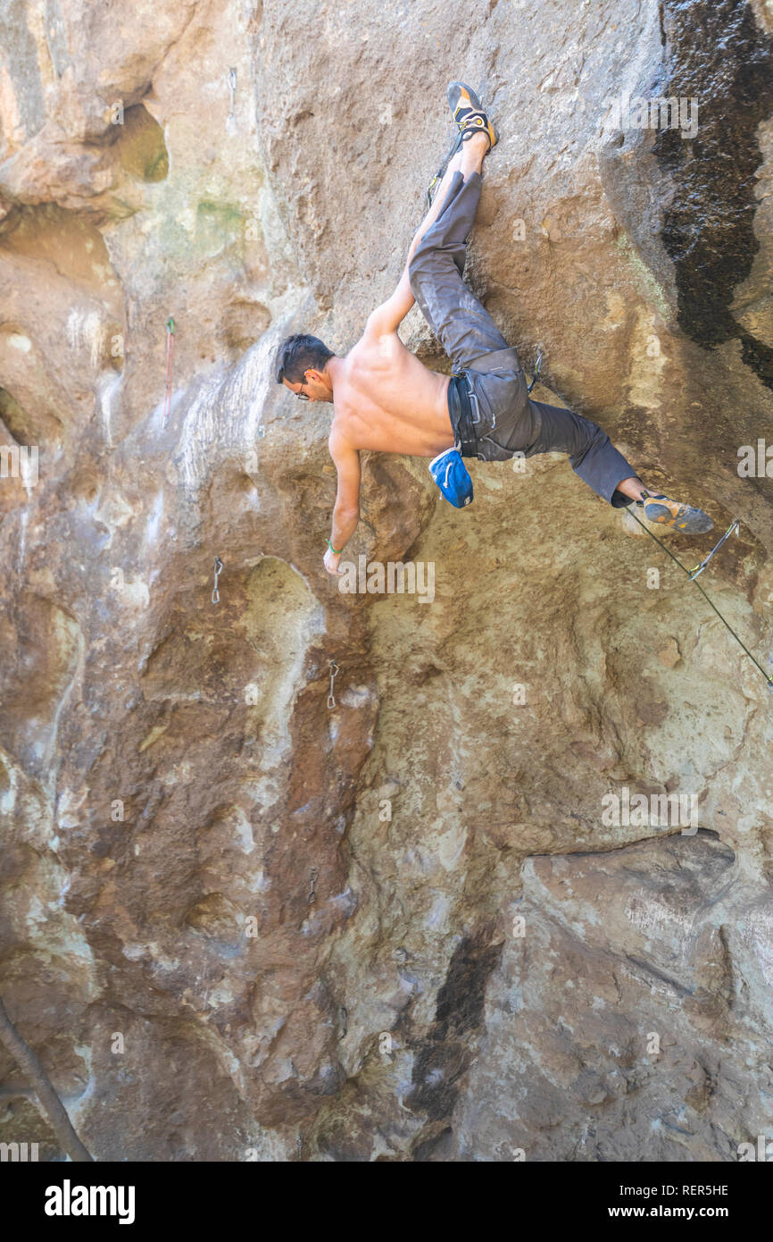 Praticare l'arrampicata su roccia sport estremo all'interno delle montagne Ande in una scogliera. Un arrampicatore maschio fa i movimenti duri con tenacia e fiducia Foto Stock