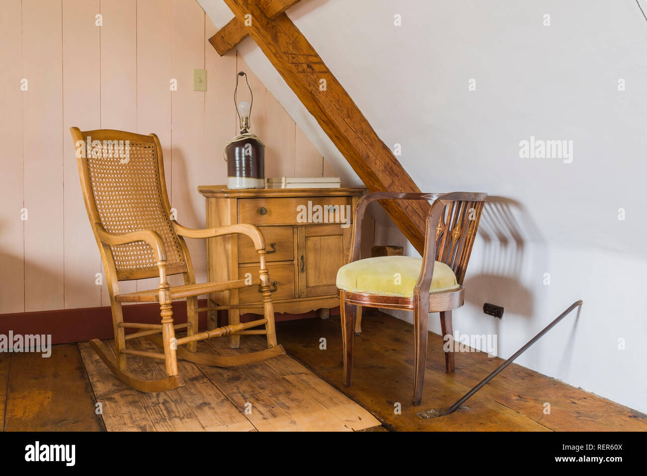 Alto antiquariato in legno indietro Sedia a dondolo e di colore giallo chiaro sedia imbottita accanto a cassettiera in camera attico all'interno di vecchi 1809 regime francese stile home Foto Stock
