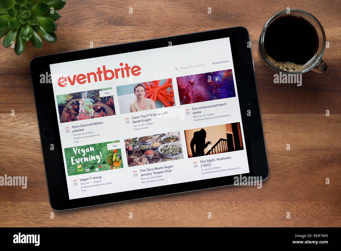 Il sito web di Eventbrite è visto su un tablet iPad, su di un tavolo di legno lungo con un caffè espresso e una pianta di casa (solo uso editoriale). Foto Stock