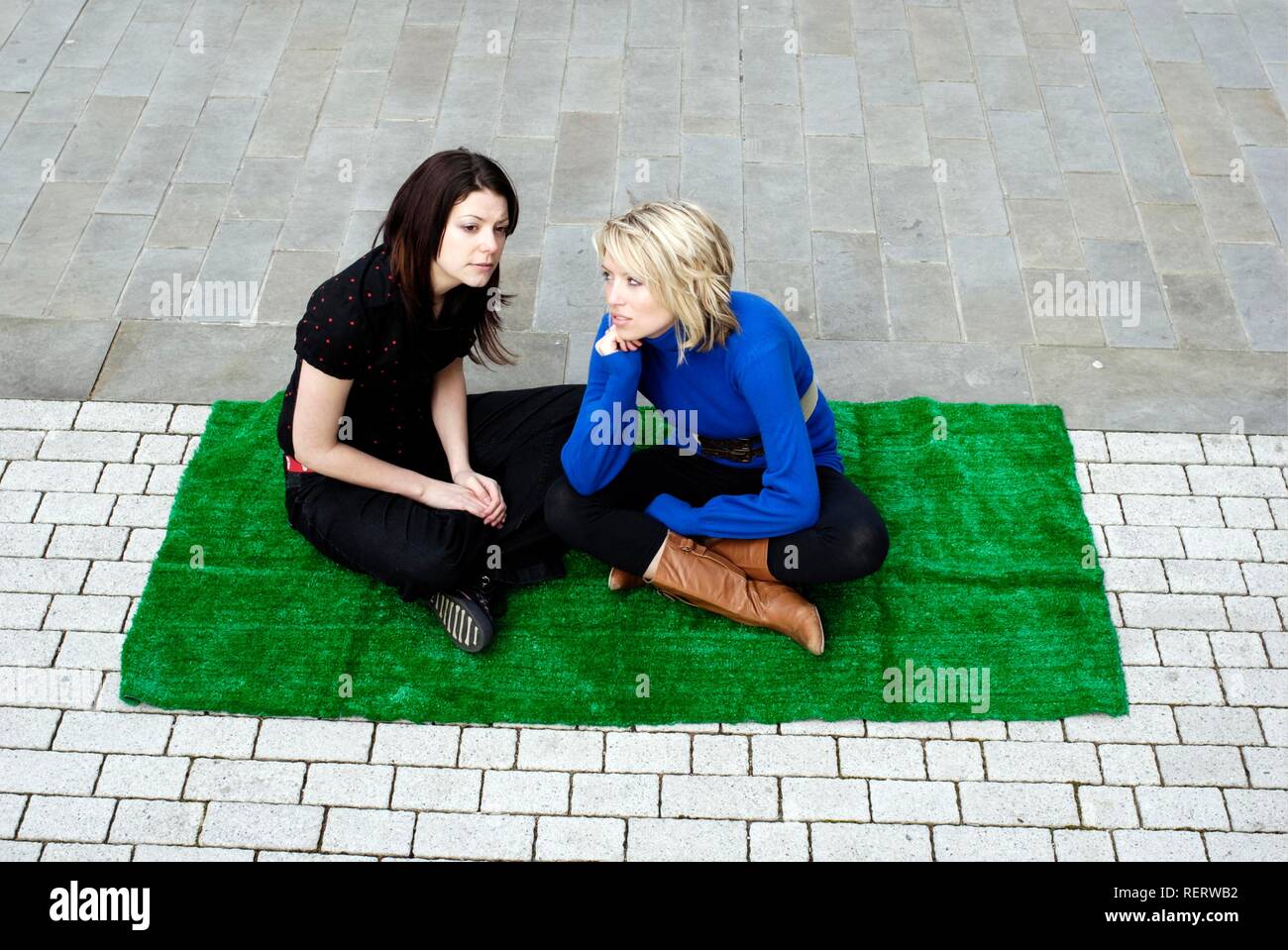 Due giovani donne creando il proprio santuario verde in città con qualche erba artificiale Foto Stock