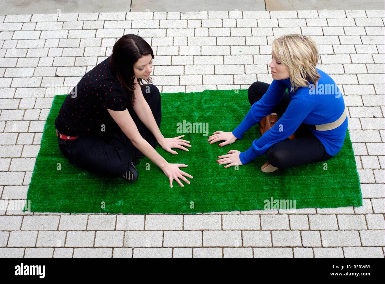 Due giovani donne creando il proprio santuario verde in città con qualche erba artificiale Foto Stock