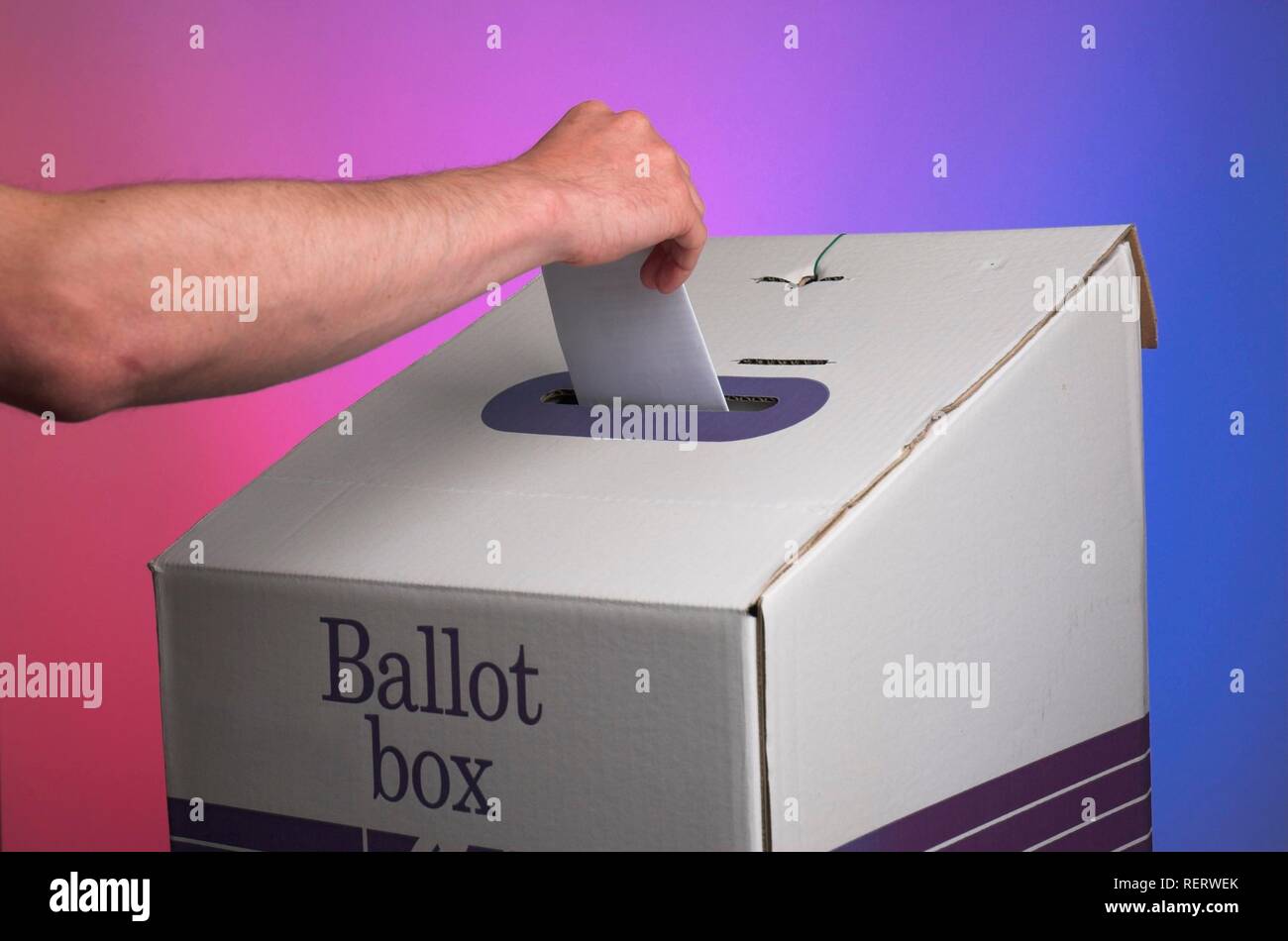 La caduta di mano di votare in un urna elettorale contro sfondo con colori opposti dello spettro politico Foto Stock