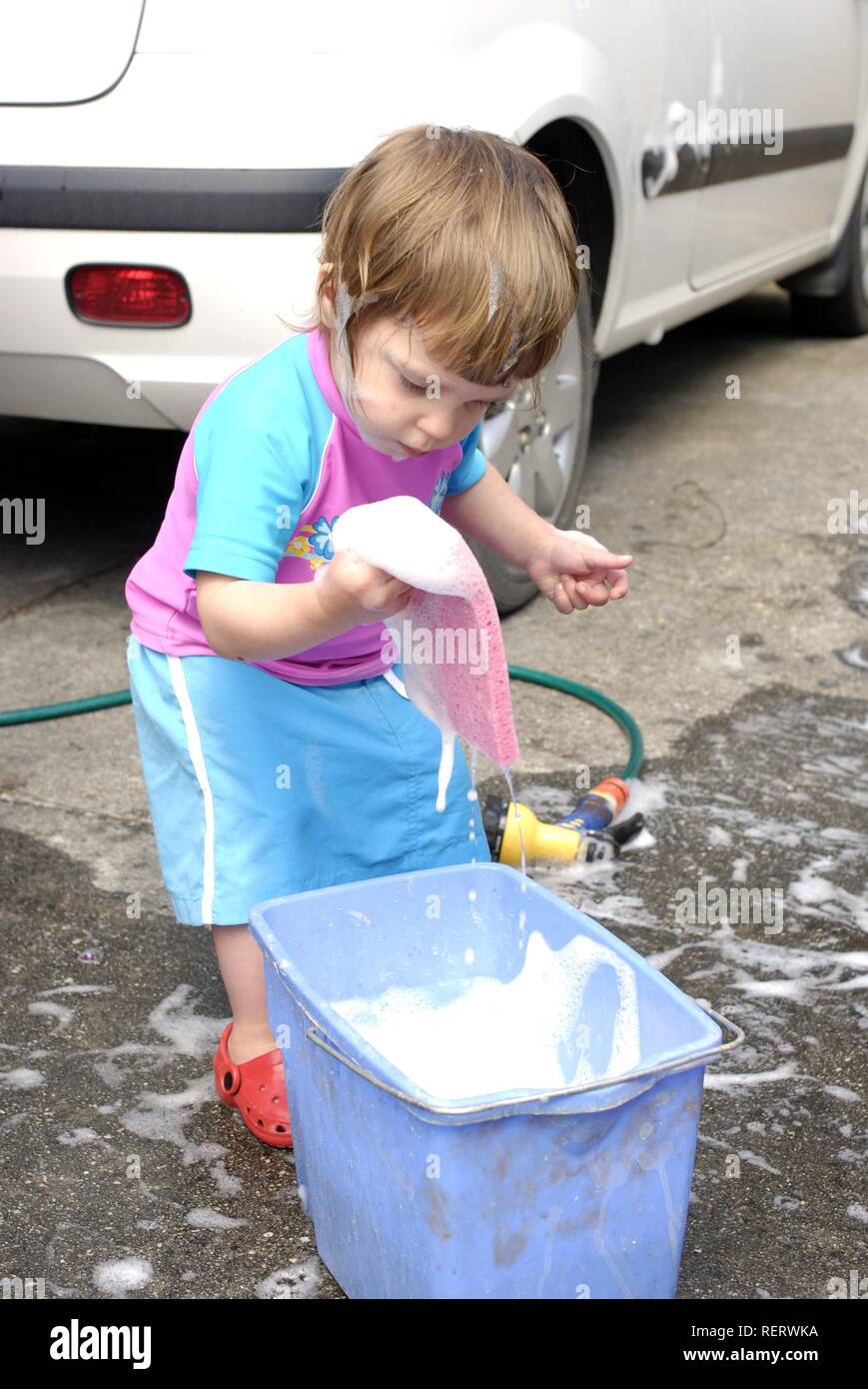 Due anno vecchia ragazza divertirsi aiutando a lavare la macchina di famiglia Foto Stock