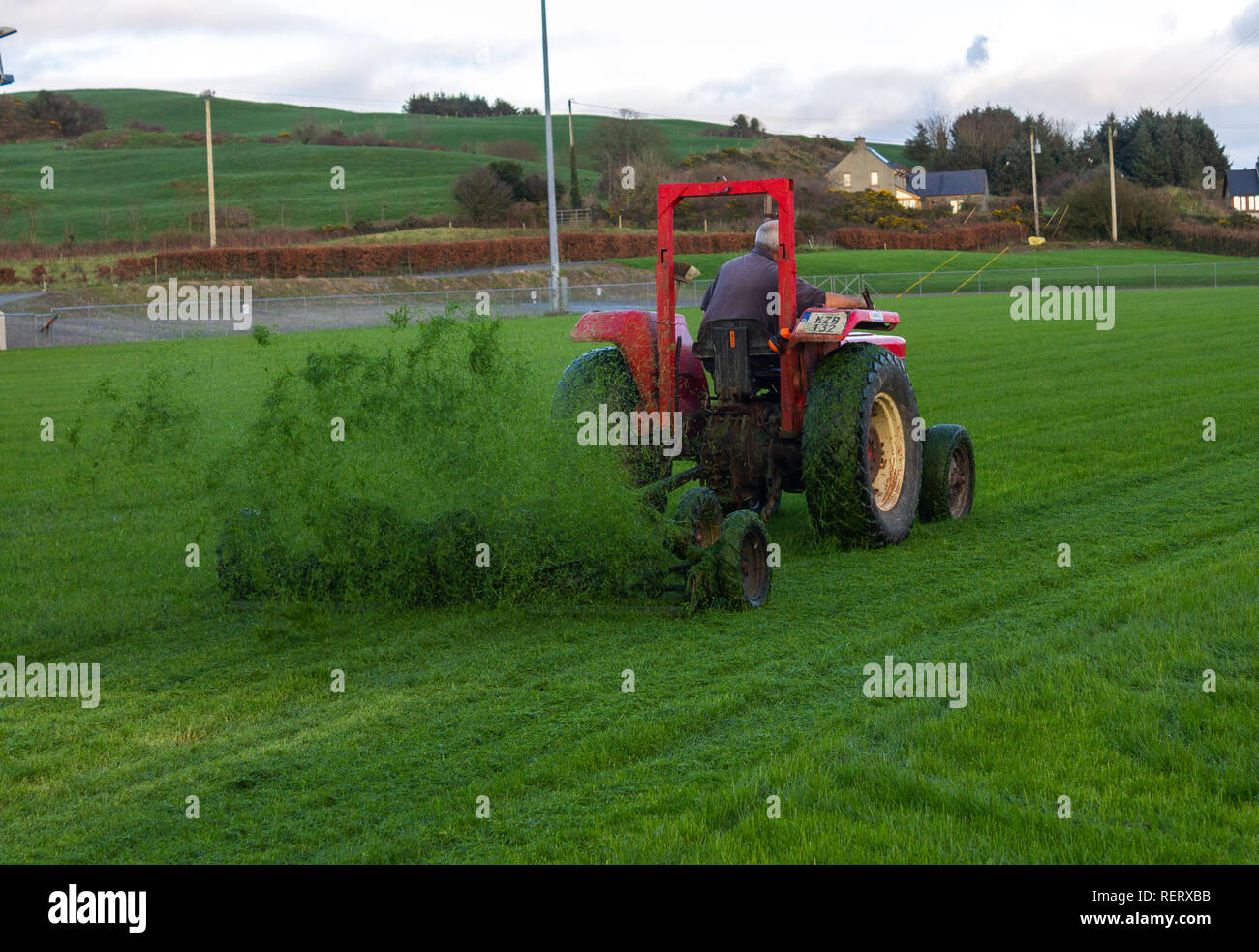 Un uomo su un trattore tirando una serie di falciatrici singole Foto Stock