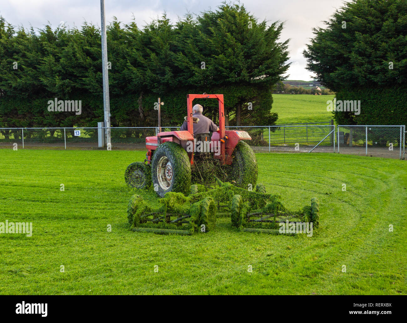 Un uomo su un trattore tirando una serie di falciatrici singole Foto Stock