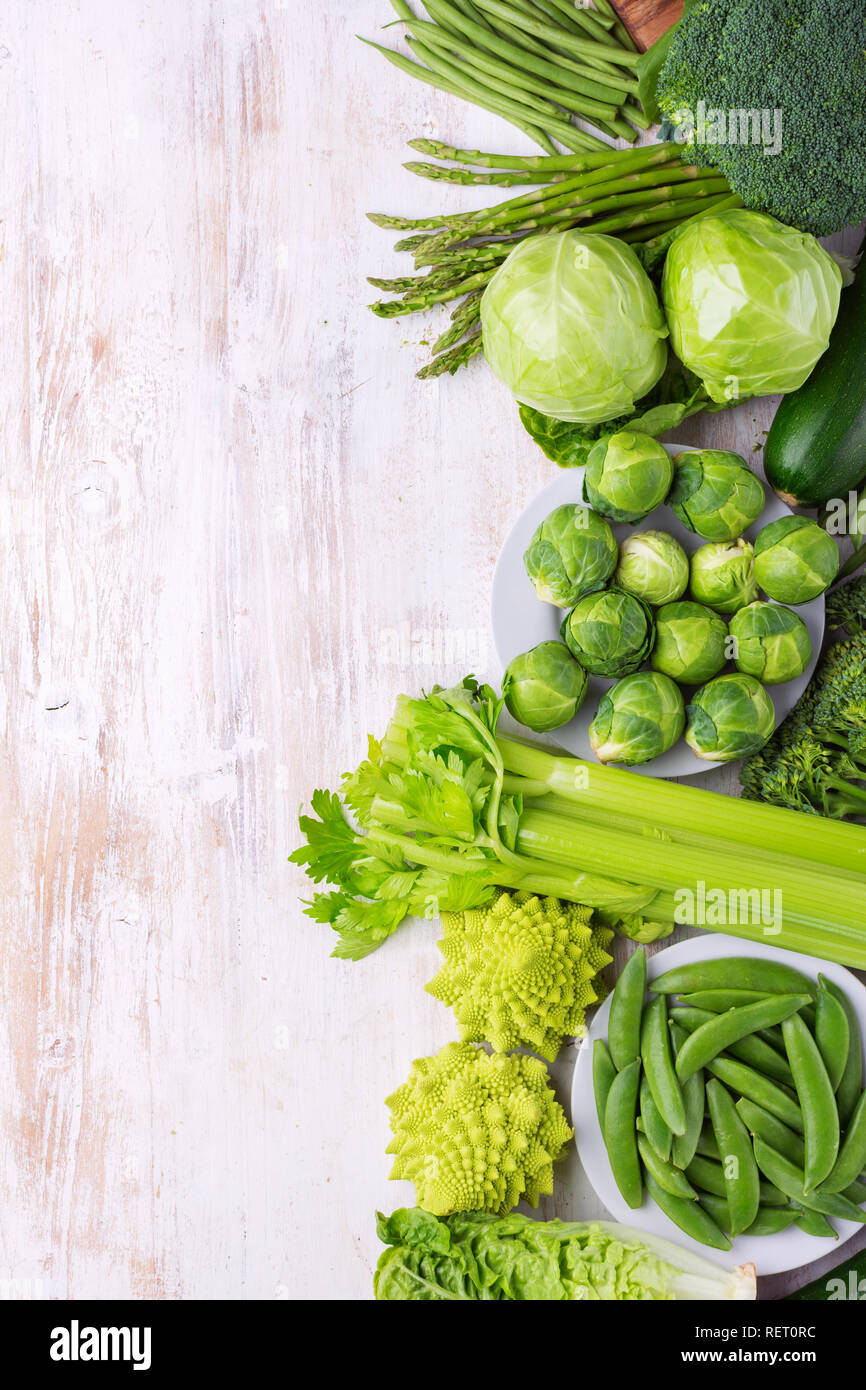 Mangiare sano concetto vegan. Verdure verdi sul tavolo bianco broccoletti piselli avocado fagioli zucchine cavolo cinese sedano, vista dall'alto, copia spazio, sel Foto Stock