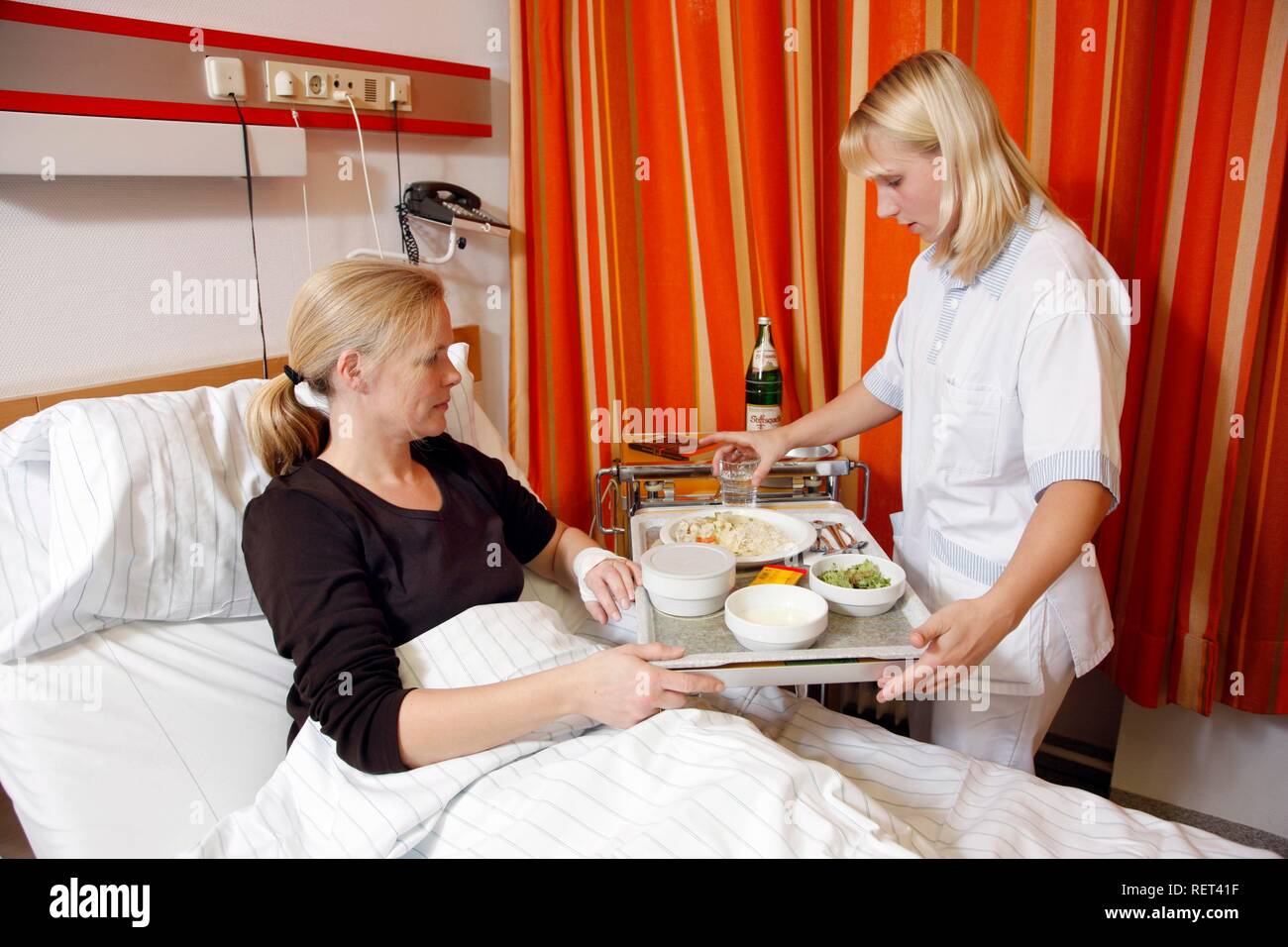 Infermiere portando un paziente in un letto di ospedale il pranzo Foto Stock