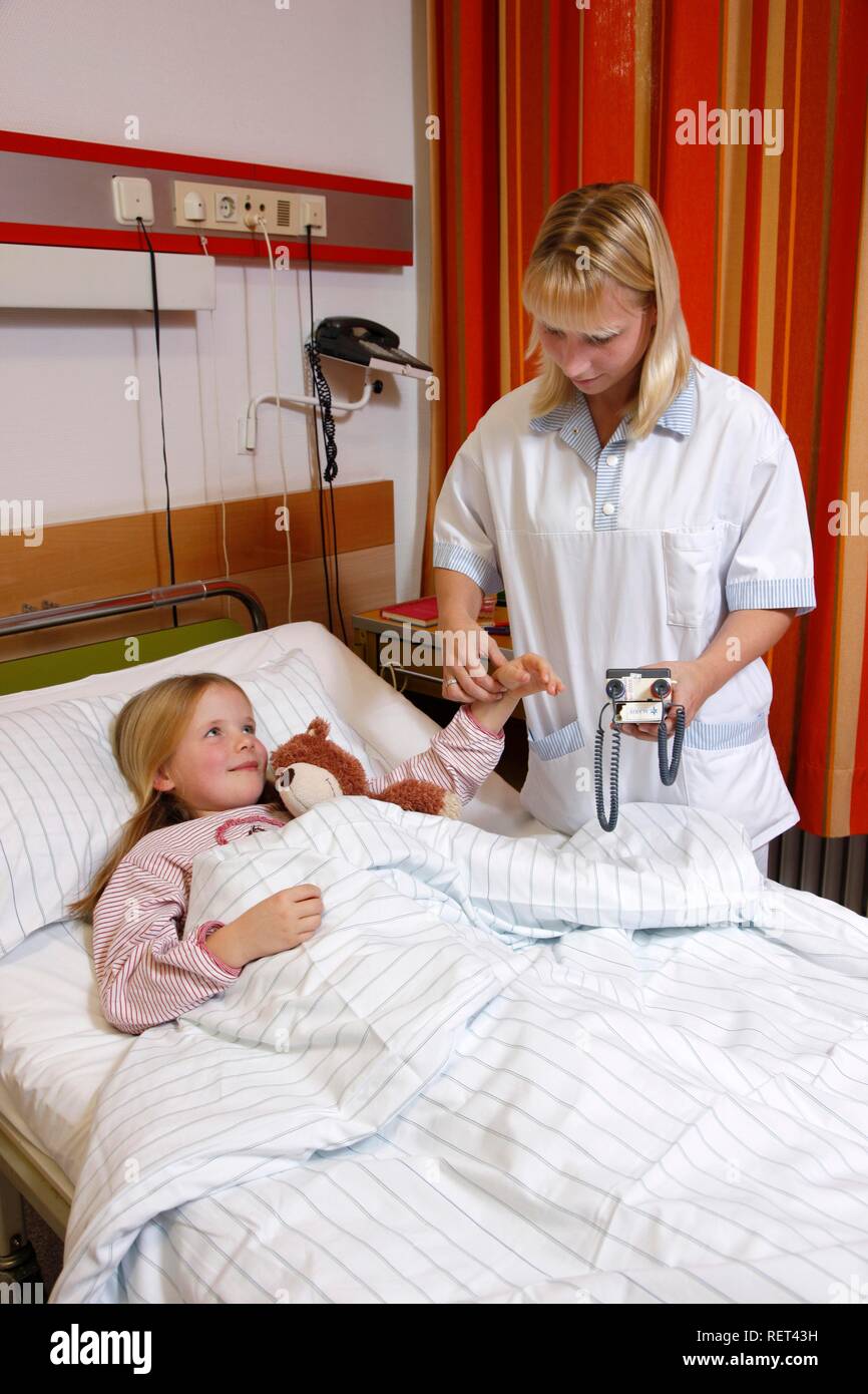 L'infermiera tenendo la frequenza del polso di un paziente giovane, 7 anni, in ospedale Foto Stock