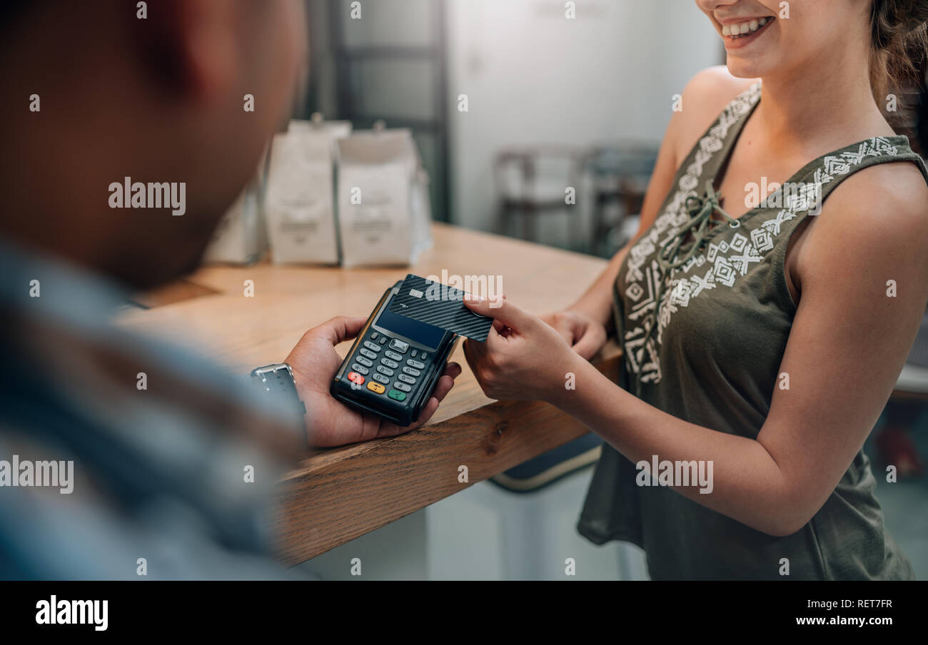 Cameriere accpeting carta di credito per il pagamento senza contatto. Il cliente effettuando il pagamento attraverso la tecnologia NFC carta di credito Foto Stock