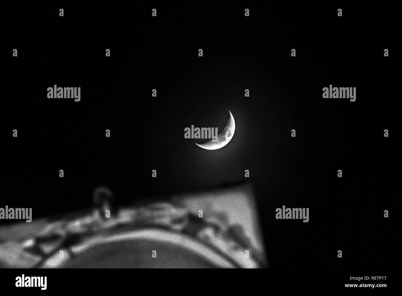 Guardando una luminosa falce di luna attraverso un telescopio; sfondo nero Foto Stock