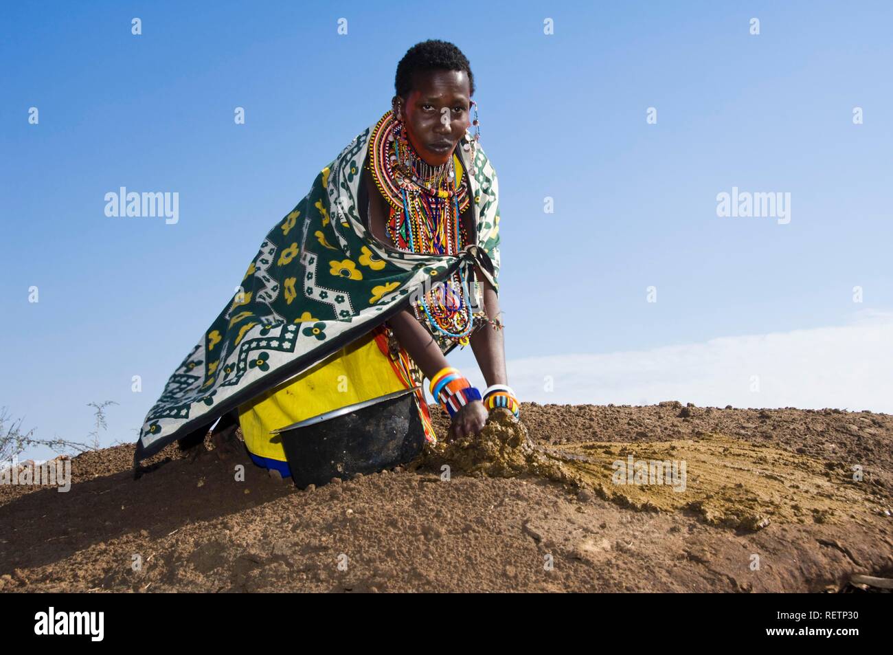 Masai donna la riparazione del tetto di una capanna con sterco di vacca, il Masai Mara, Kenya, Africa orientale Foto Stock