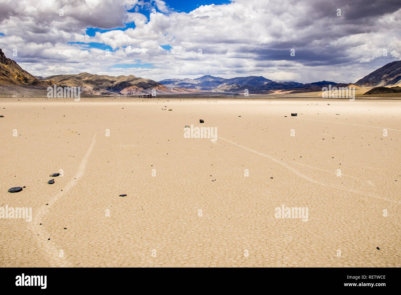 Lo spostamento delle rocce e le loro tracce in autodromo Playa; le montagne e le nuvole paesaggio sullo sfondo; Parco Nazionale della Valle della Morte, California Foto Stock