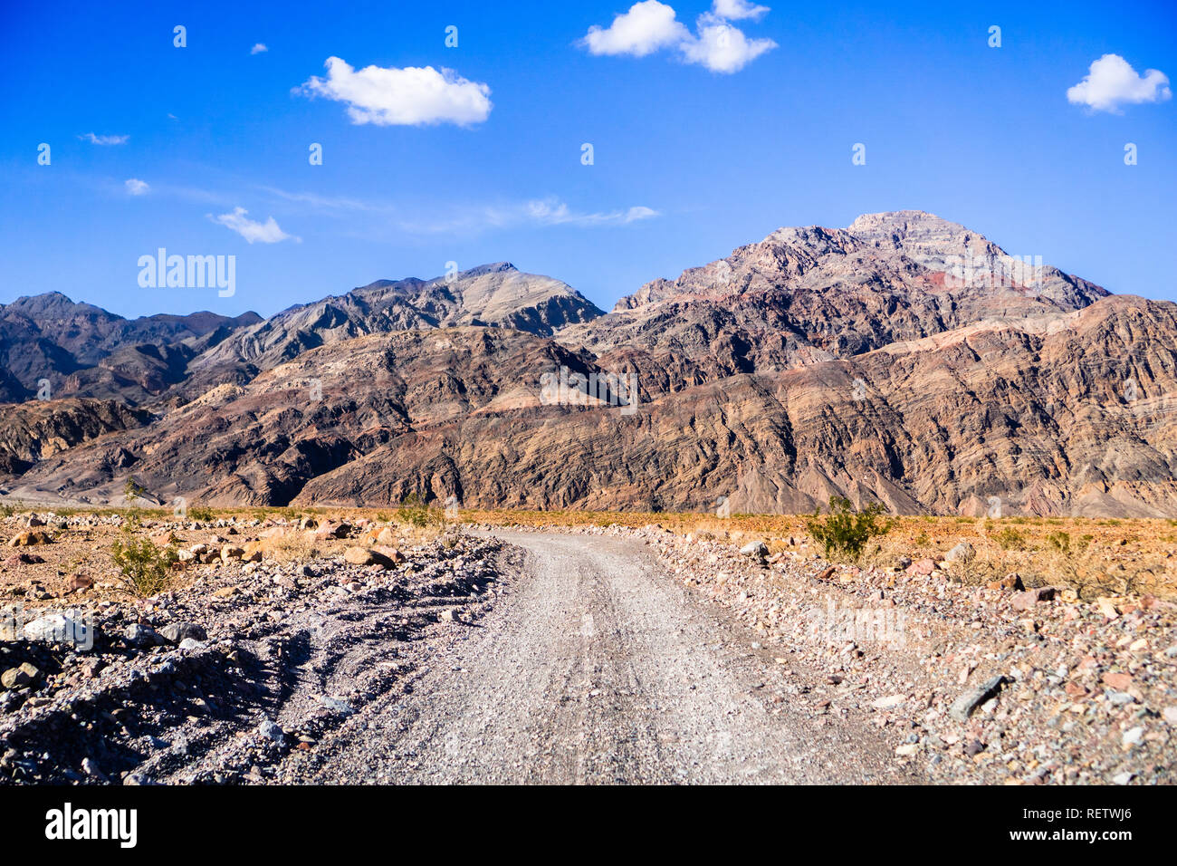 La guida su una strada sterrata verso l'entrata a Tito Canyon, il Parco Nazionale della Valle della Morte; ripide montagne sullo sfondo; California Foto Stock
