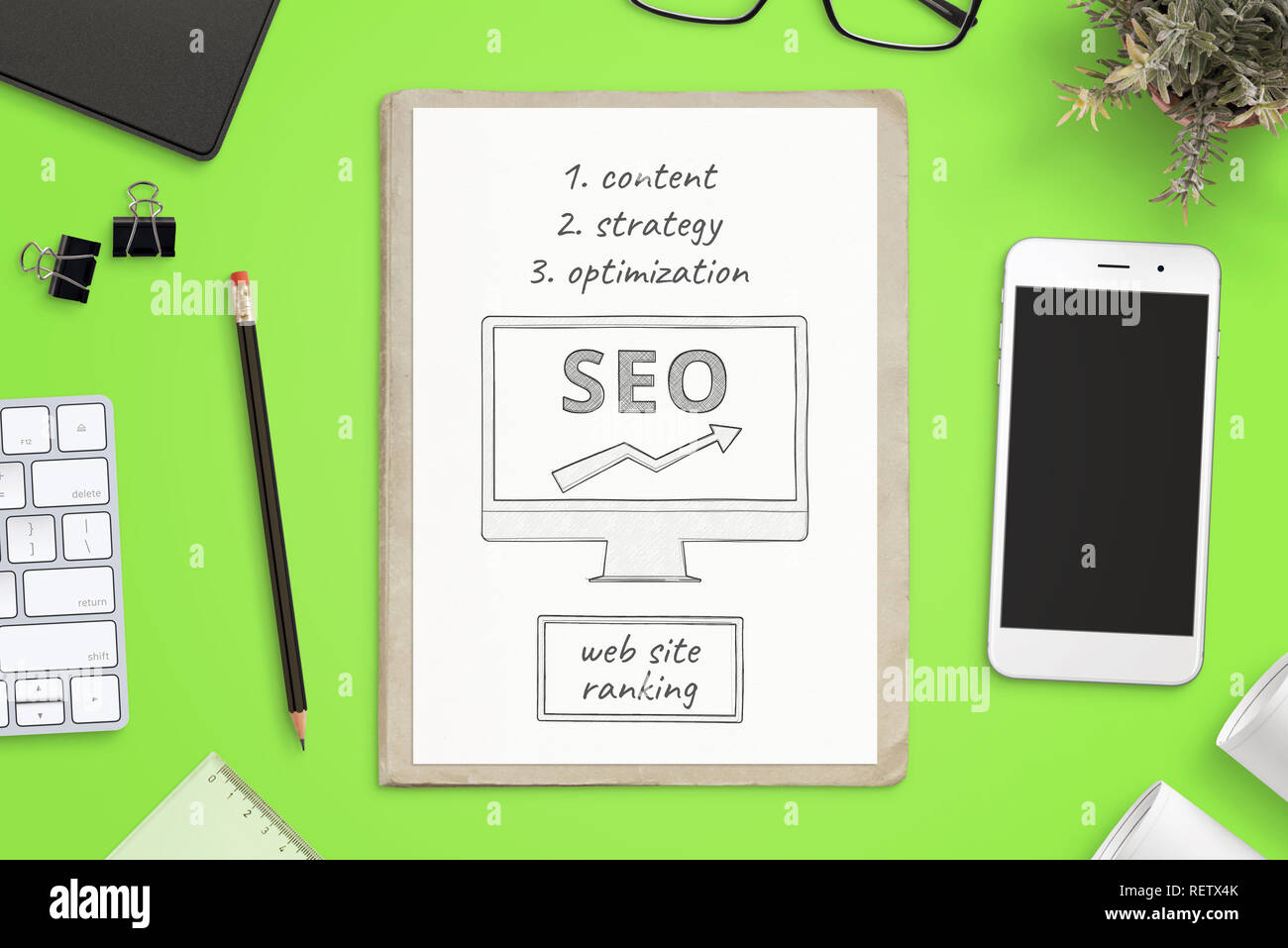 Ottimizzazione per i motori di ricerca obiettivi schizzo su carta e smart phone mockup accanto a verde sulla scrivania in ufficio. Concetto di SEO composizione. Vista dall'alto. Foto Stock