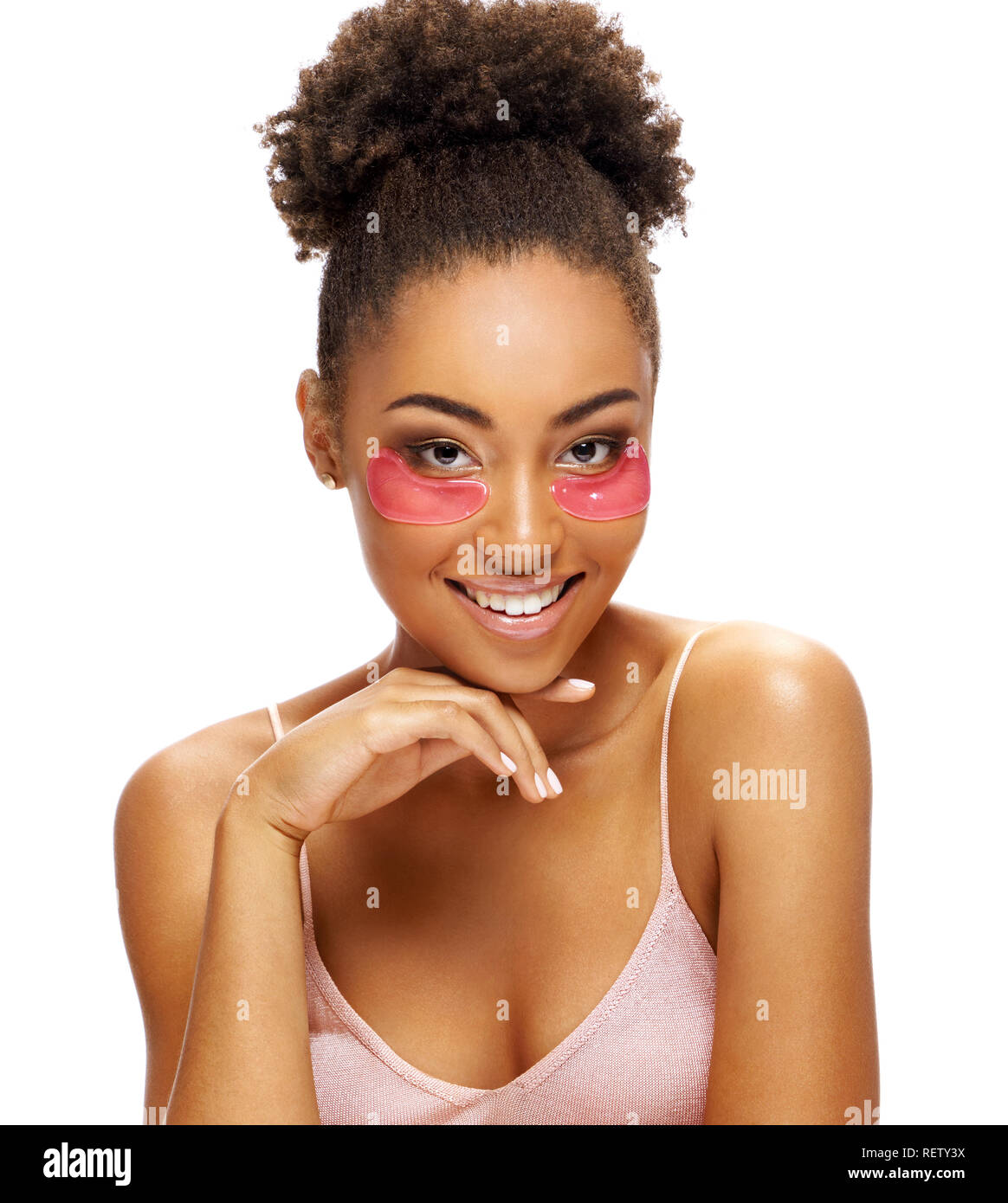 Ragazza sorridente con occhio rosa patch sul suo viso. Foto di African American Girl di toccare la sua pelle impeccabile su sfondo bianco. Cura della Pelle concept Foto Stock