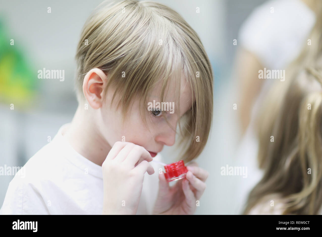 Un bambino di età scolare è la miscelazione in un recipiente di un dente rosso-gel di pulizia. Foto Stock