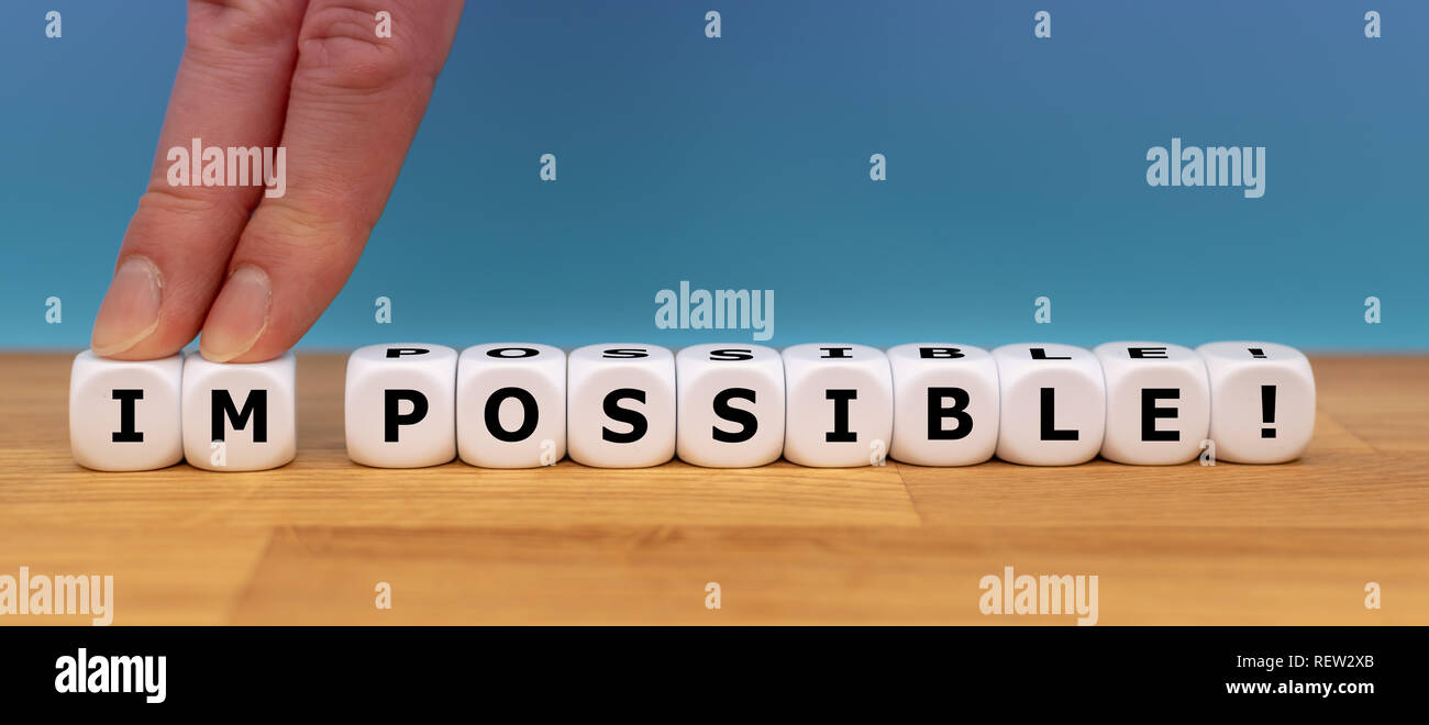 Dadi forma la parola 'impossibile' mentre due dita spingere le lettere "IM" di distanza al fine di modificare la parola "possibile". Foto Stock