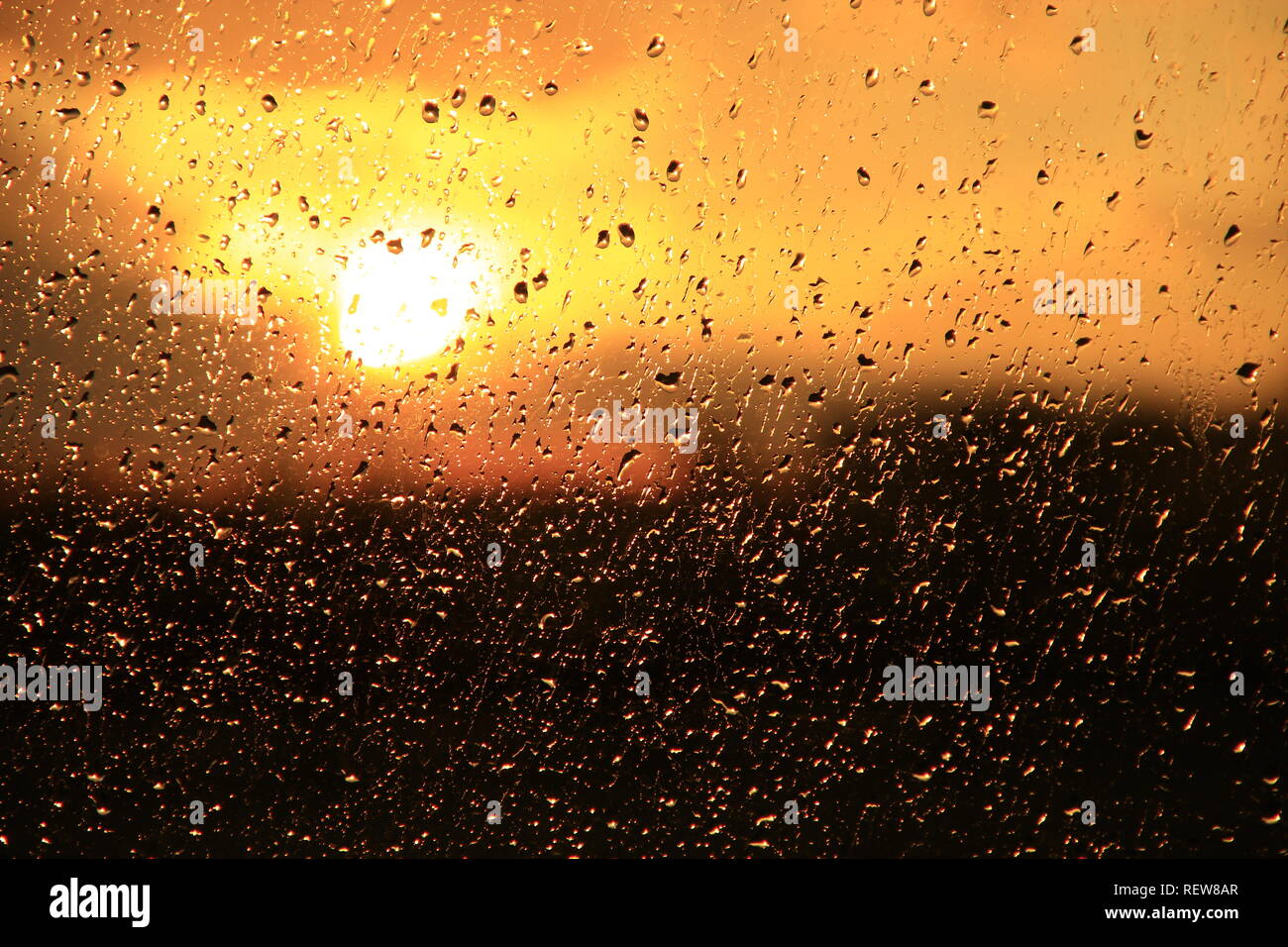 La pioggia al di fuori della finestra sul background del tramonto. Gocce di pioggia sul vetro durante la pioggia. Tramonto al di fuori finestra durante la pioggia. Texture brillanti di gocce di acqua Foto Stock
