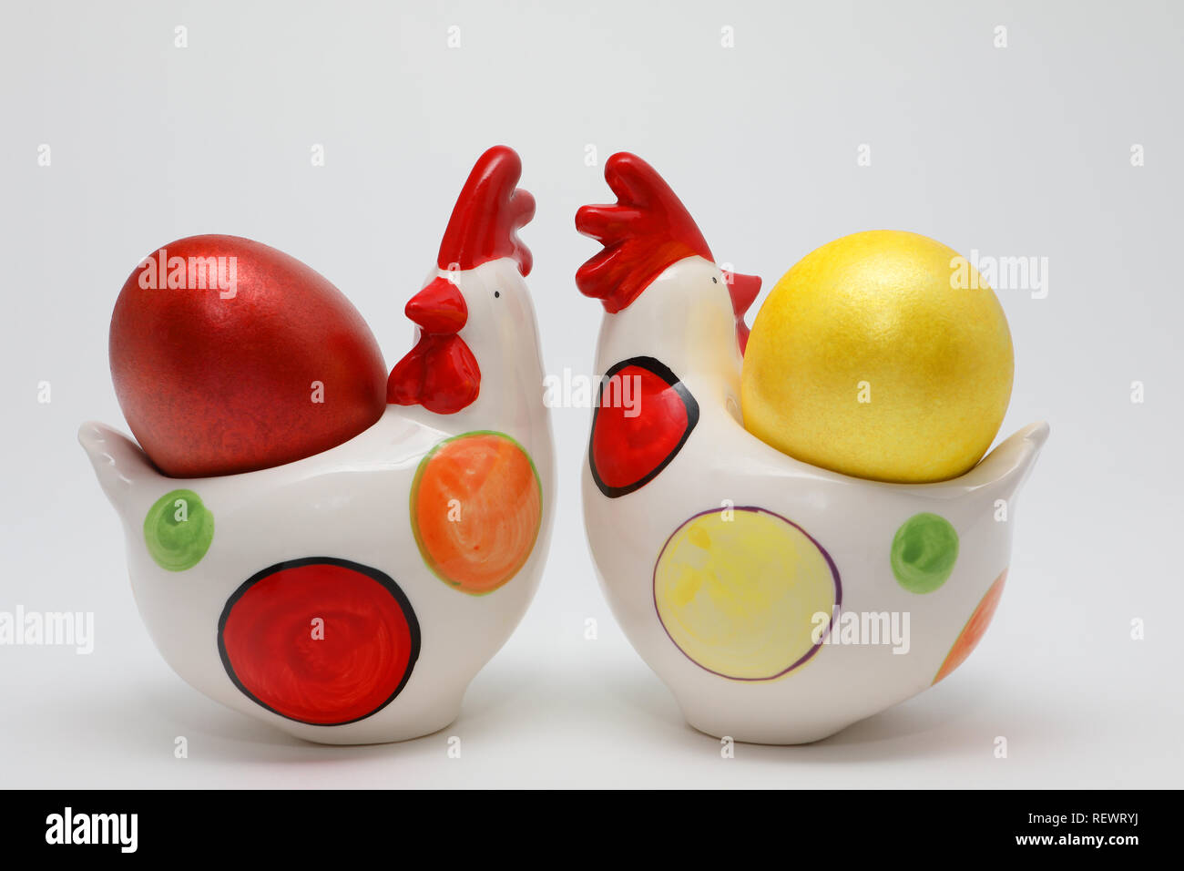 Colorate le uova di Pasqua in due galline giocattolo su sfondo bianco, la molla dell'immagine. Concetto di pasqua. Foto Stock