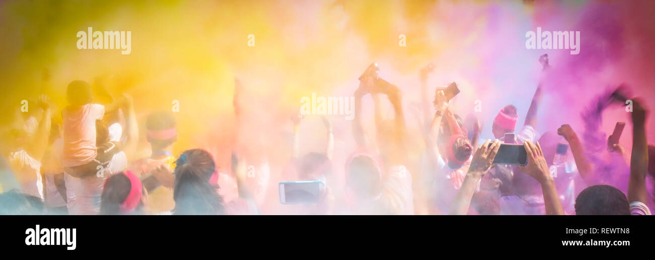 Una folla entusiasta celebra lanciando polvere colorata nell'aria. Foto Stock