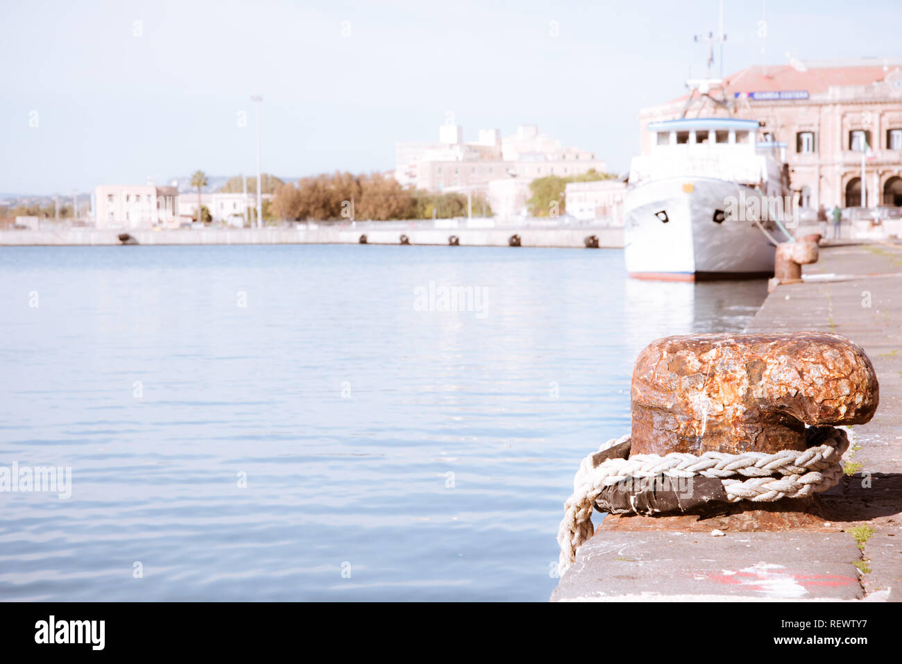 La cima di ormeggio con una estremità annodata legato attorno un gancio su un molo di cemento/ Nautica Foto Stock