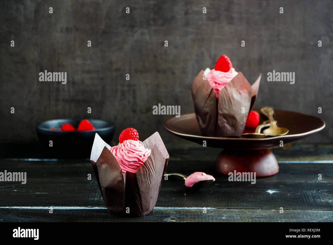 Tortine. Tortini di glassa decorata con lampone e rosa di crema di formaggio Foto Stock