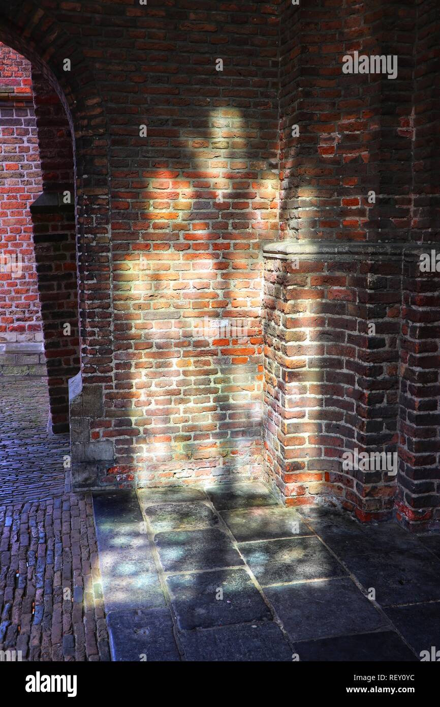La luce del sole brilla attraverso una finestra ad arco, colata forme interessanti su un vecchio muro di mattoni, Amsterdam, l'Europa. Foto Stock