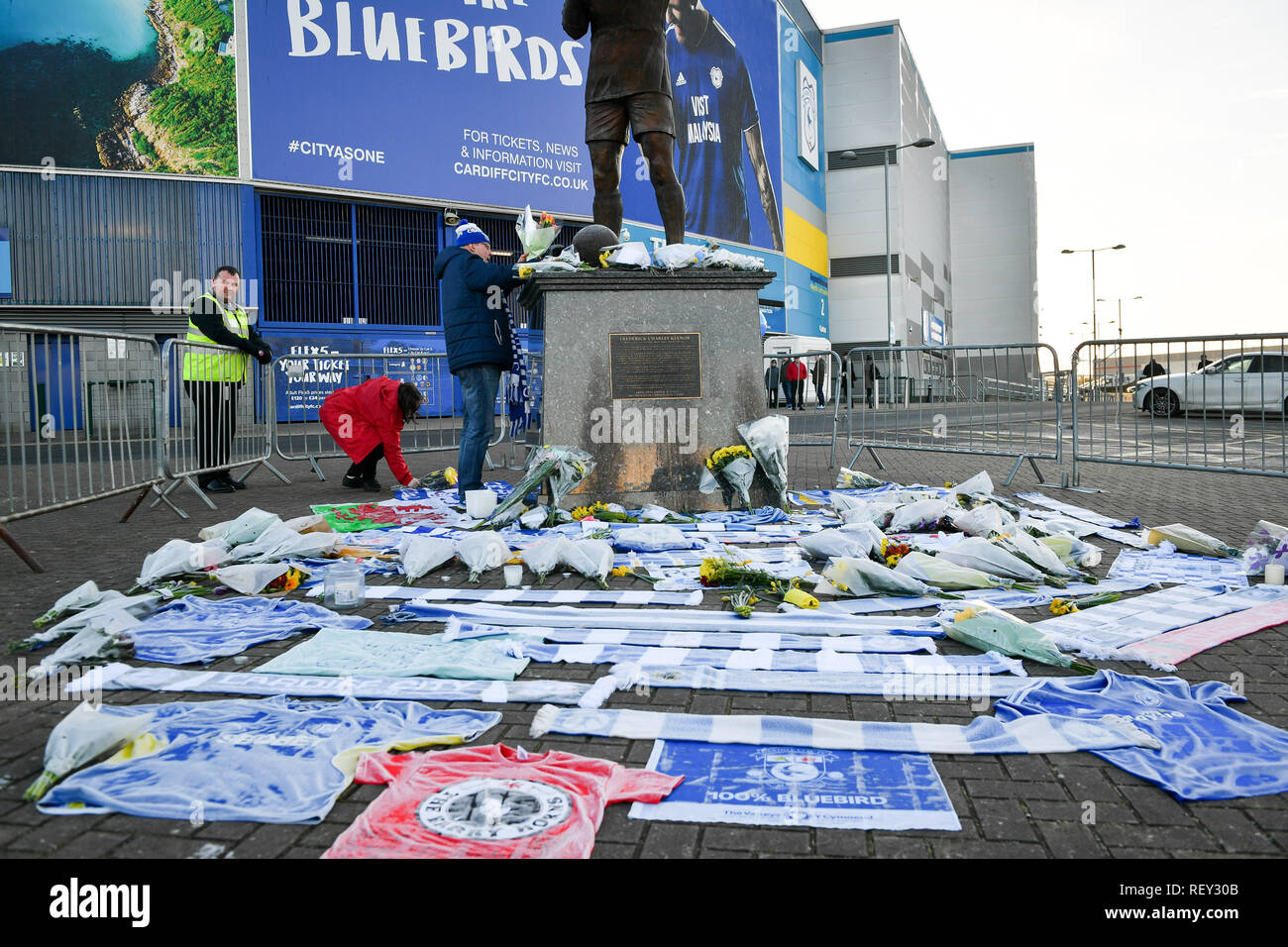 Fiori e omaggi a sinistra dalla statua di Cardiff City il calciatore Frederick Charles Keenor fuori Cardiff City Football Club dopo un piano con nuova firma Emiliano Sala a bordo sono scomparsi oltre la Manica di lunedì sera. Foto Stock