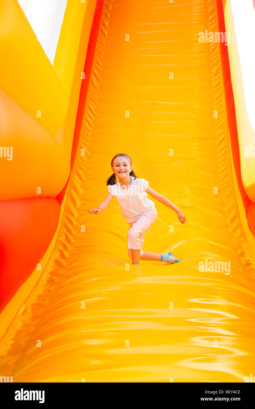 Felice bambina avente un sacco di divertimento su un castello di salto mentre lo scorrimento. Foto Stock