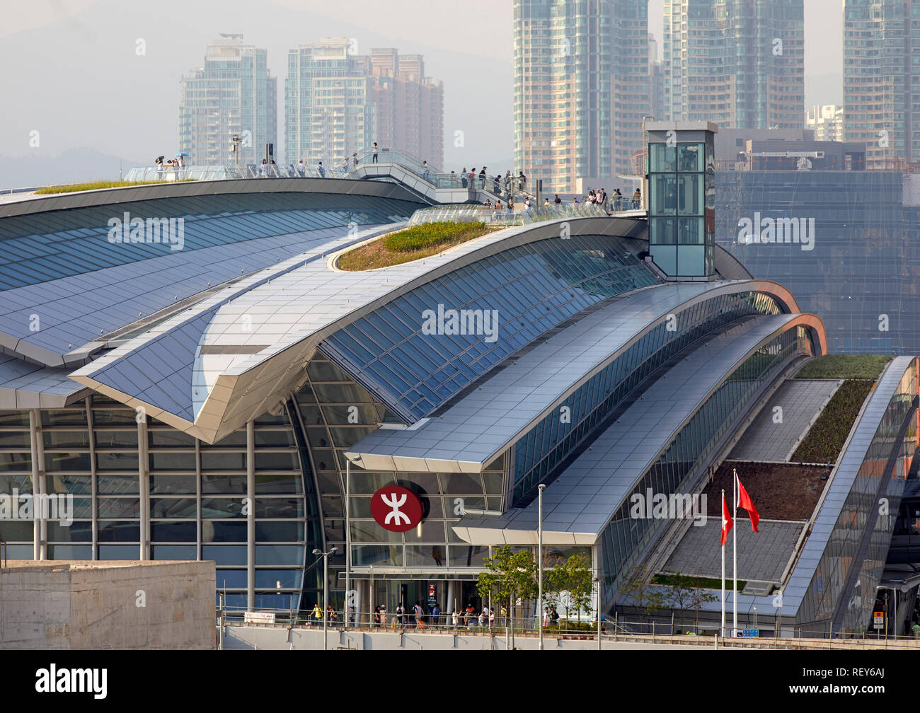 Vista distante con figure sul tetto. A ovest della stazione di Kowloon, Hong Kong, Cina. Architetto: Andrew Bromberg Aedas, 2018. Foto Stock