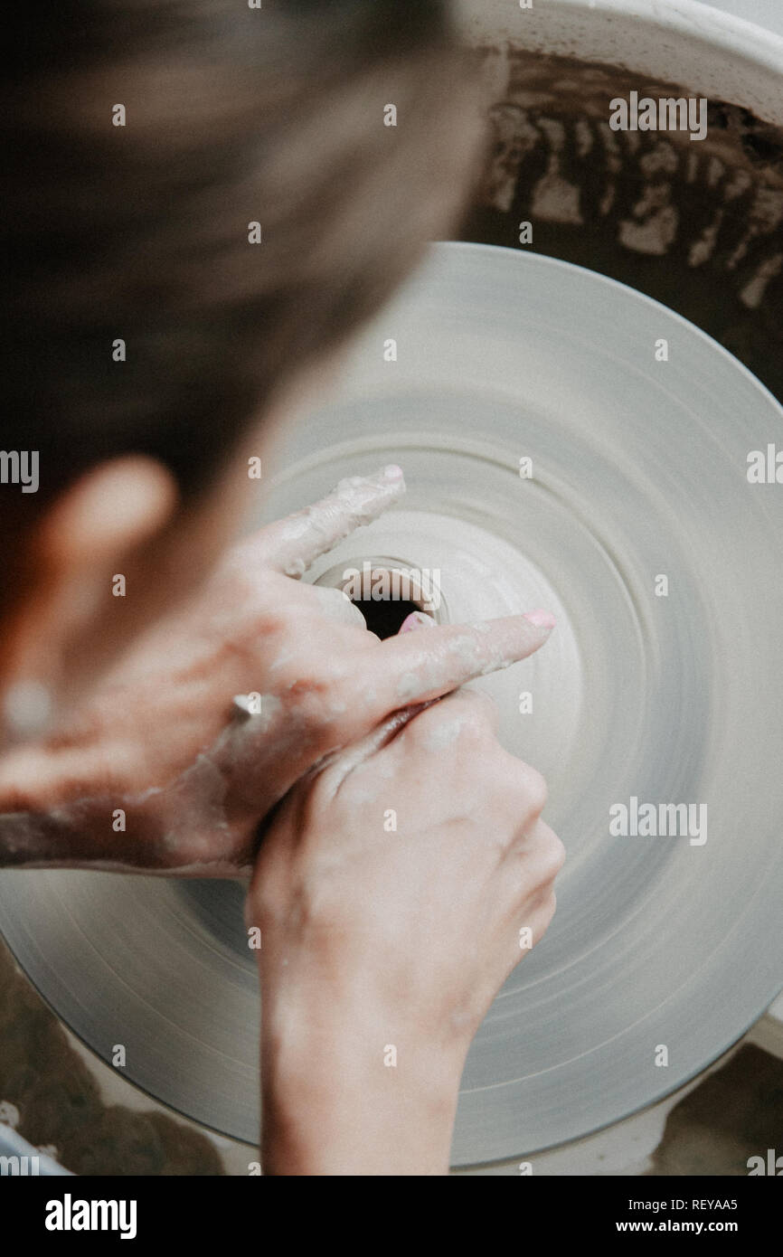 Creazione di un vaso o in un vaso di argilla bianca di close-up. Donna mani rendendo brocca di argilla su potter ruota. Foto Stock