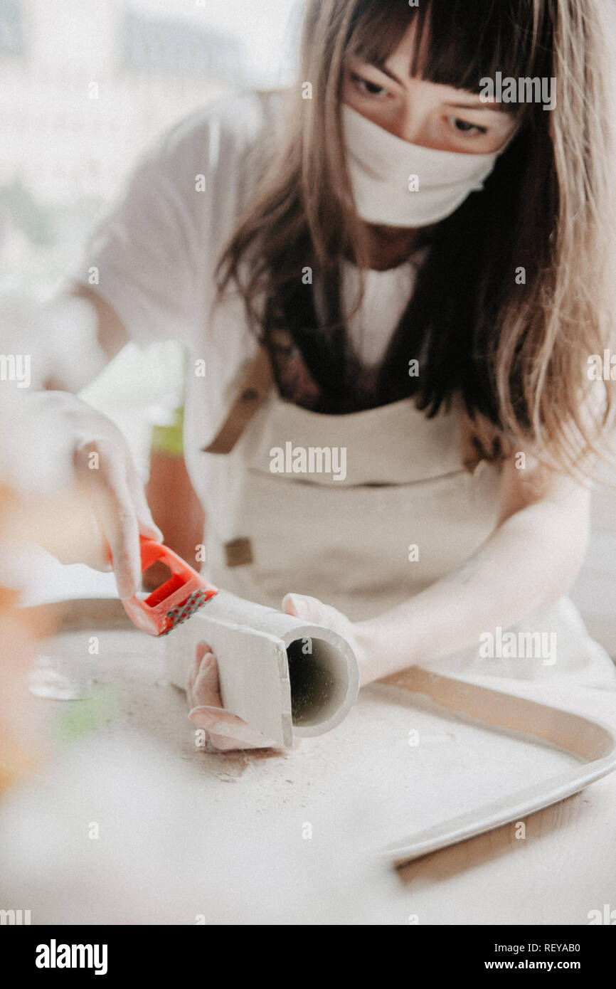Donna fare ceramica. Vista dettagliata del processo di levigatura a piastra di argilla Foto Stock