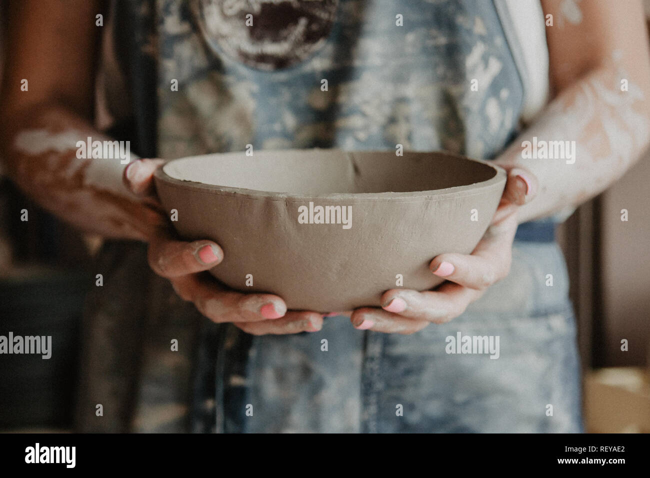 Ceramiche, argilla, arte ceramica concetto - Primo piano sulle mani del giovane maestro con la piastra grande da terra refrattaria Foto Stock