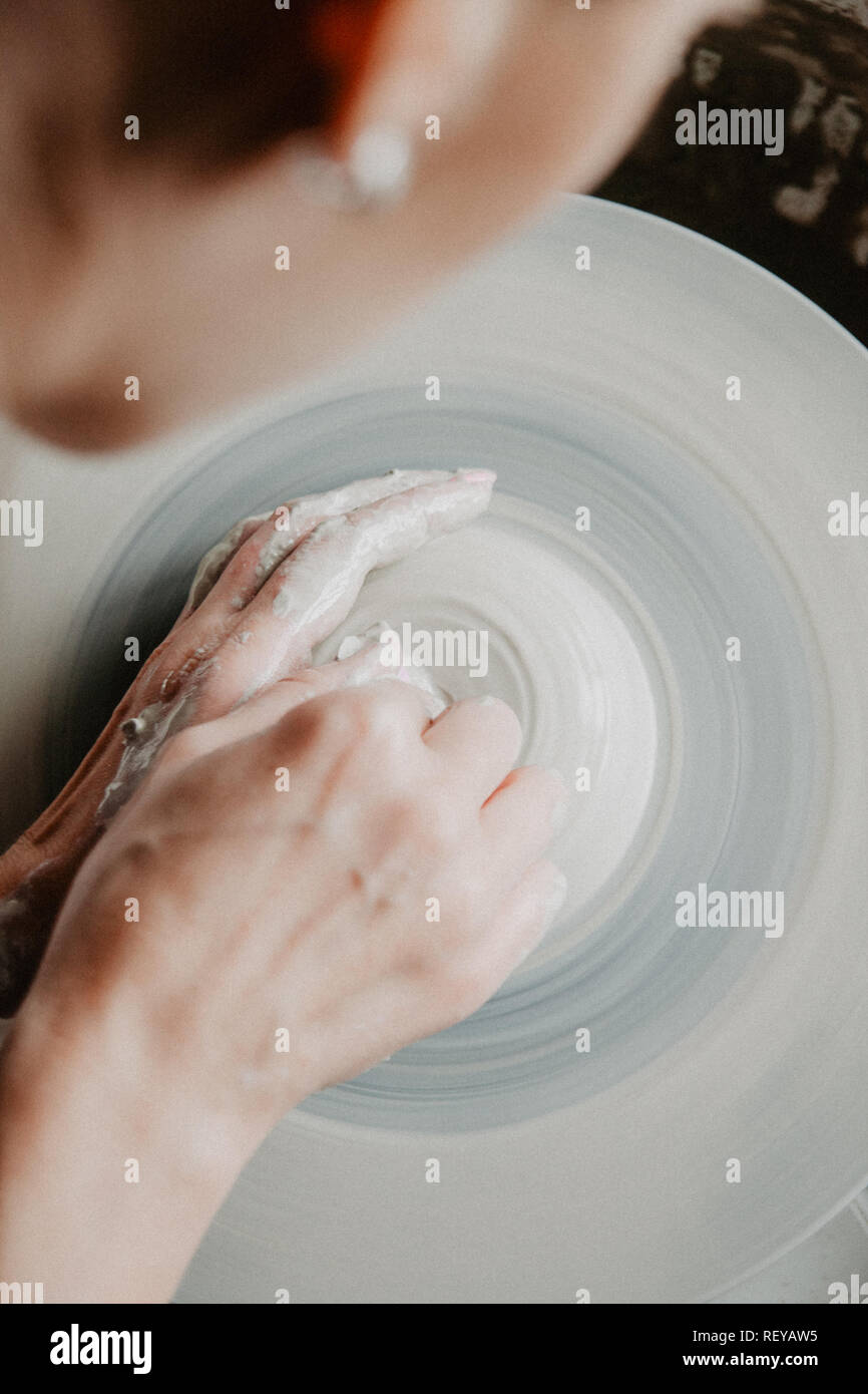 Creazione di un vaso o in un vaso di argilla bianca di close-up. Donna mani rendendo brocca di argilla. Foto Stock