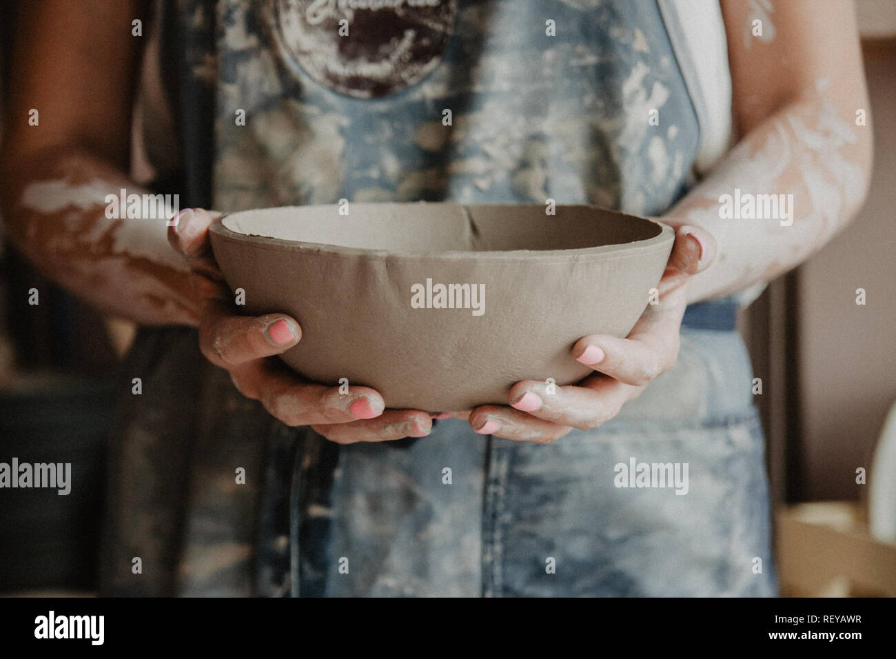 Ceramiche, argilla, arte ceramica concetto - Primo piano sulle mani del giovane maestro con la piastra grande da terra refrattaria Foto Stock
