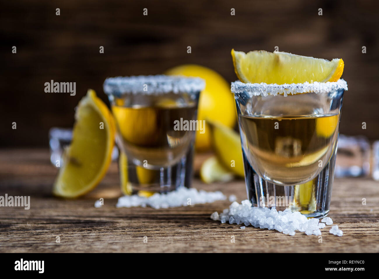 Tradizionale messicano alcool bere la tequila con limone e sale e cubo di ghiaccio sul tavolo di legno Foto Stock
