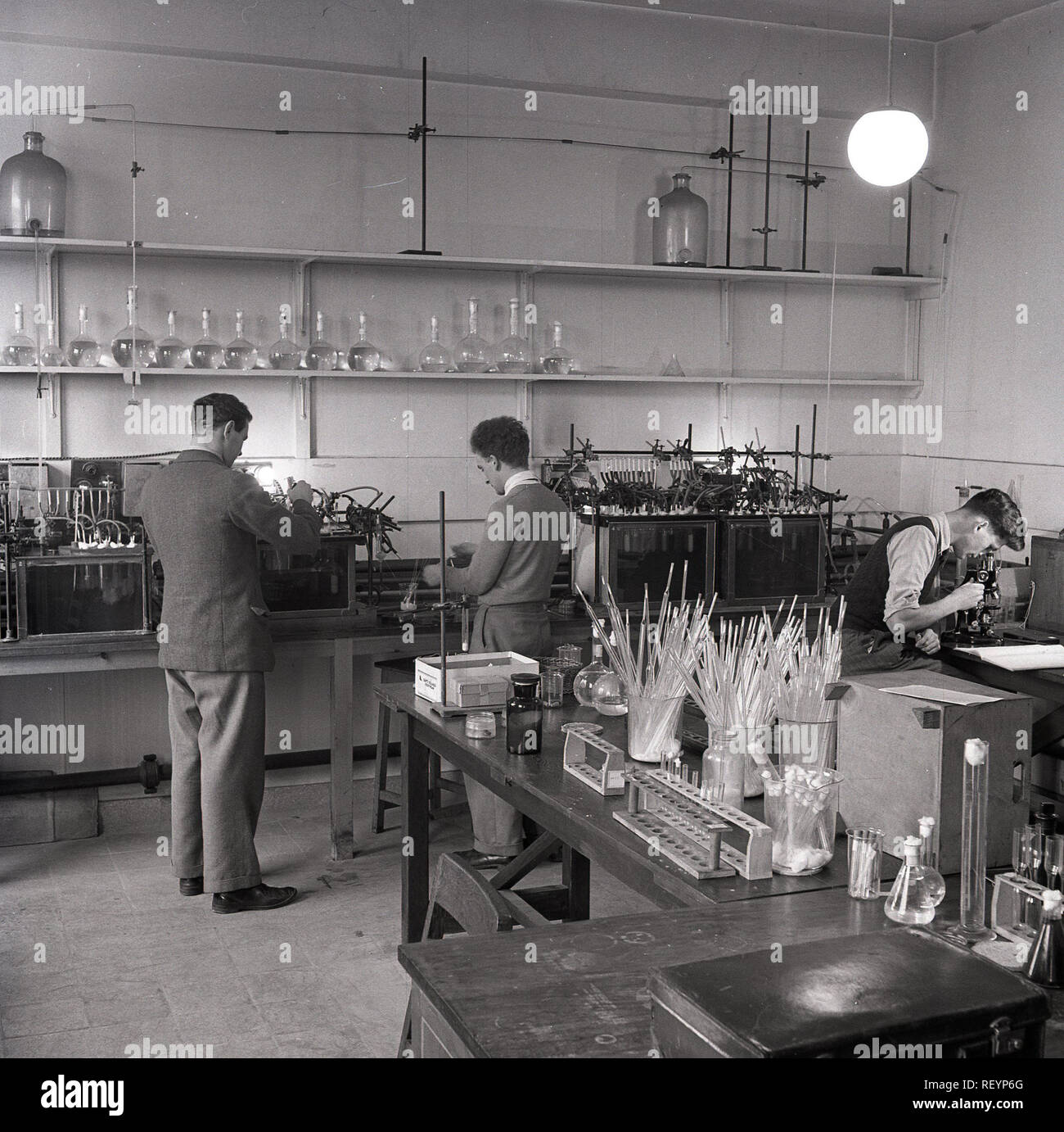 Anni '1950, storica, Università di Oxford, un laboratorio di insegnamento scientifico, studenti maschi che intraprendono esperimenti di batteri supervisionati dal professore. Foto Stock